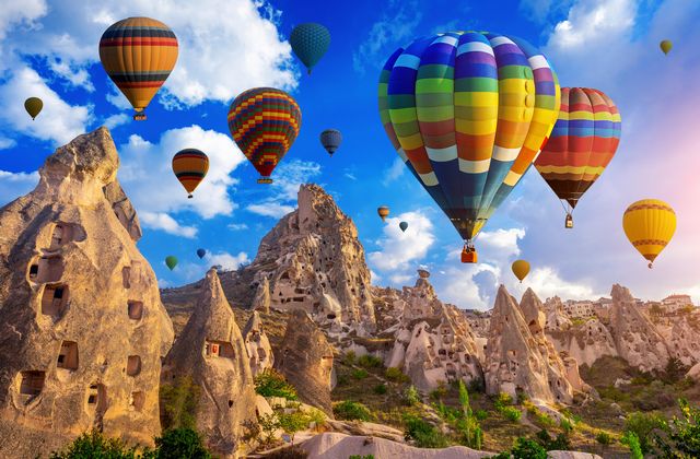 Colorful hot air balloons floating above Cappadocia's cone-shaped rock formations.