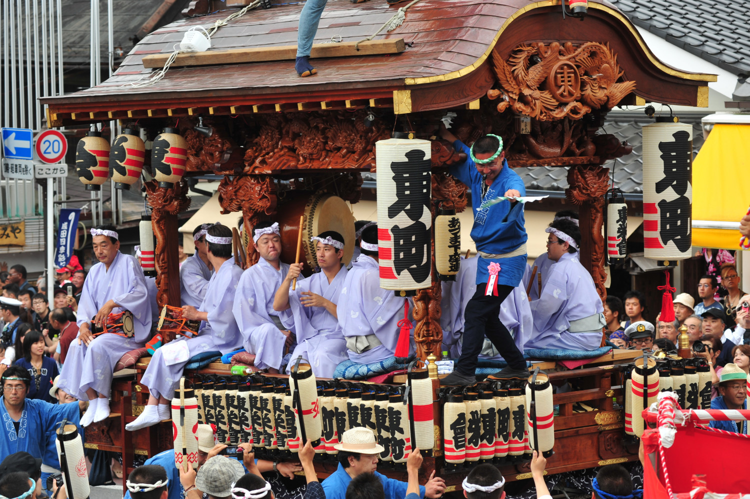 Traditional Japanese festival float (dashi) with ornately carved woodwork and lanterns, carrying participants in light purple robes