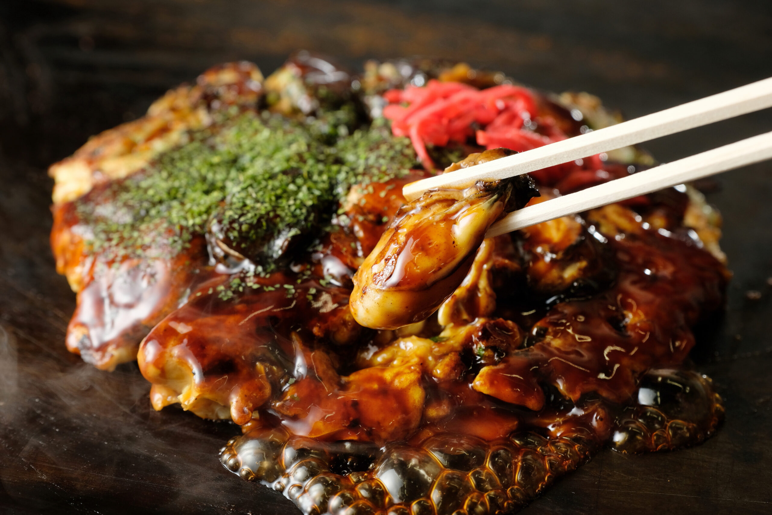 Glazed barbecued ribs being lifted with chopsticks; sauce glistening and herb garnish on top.