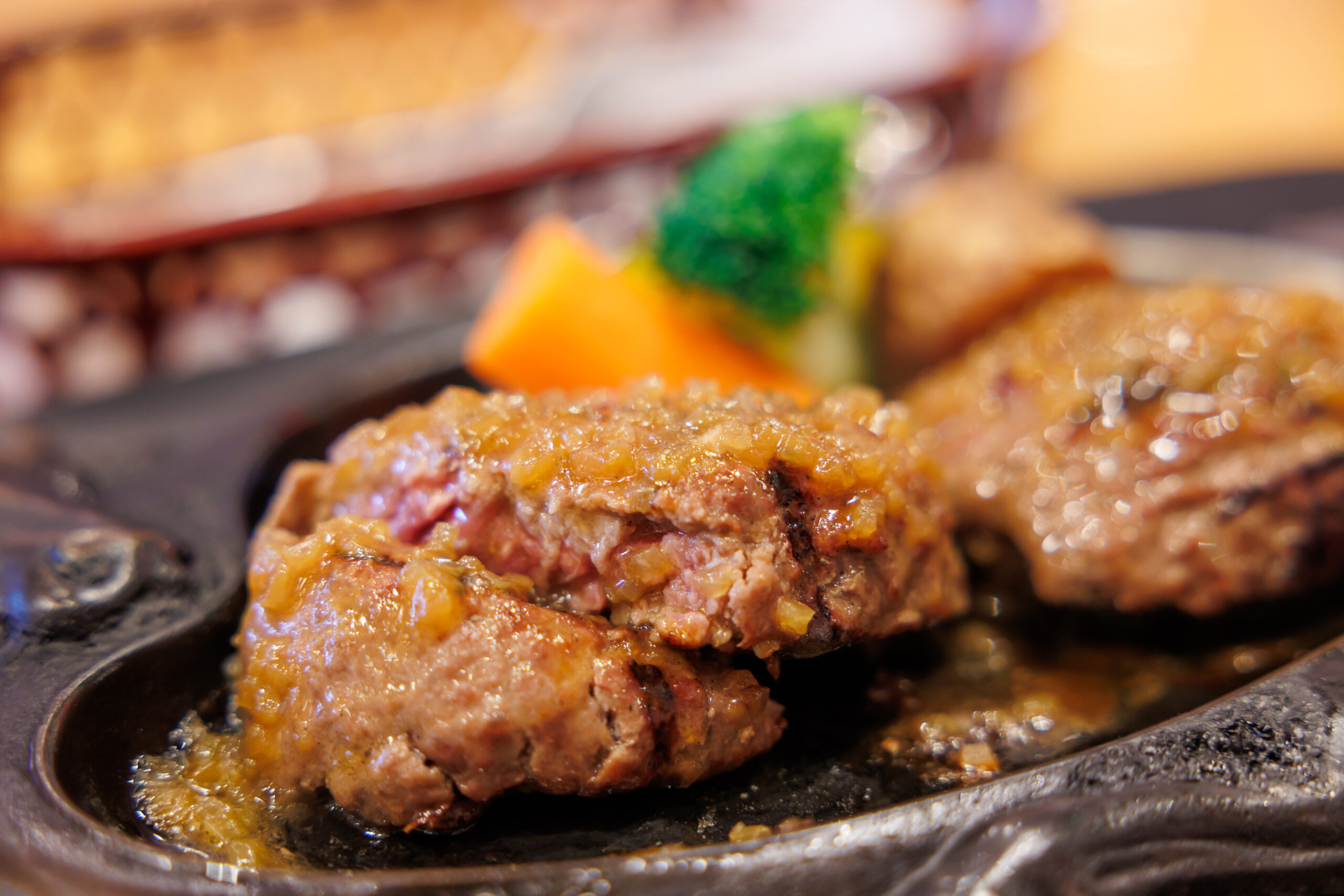 Close-up of juicy hamburger patties grilling on a hot barbecue grill, with sizzling juices.