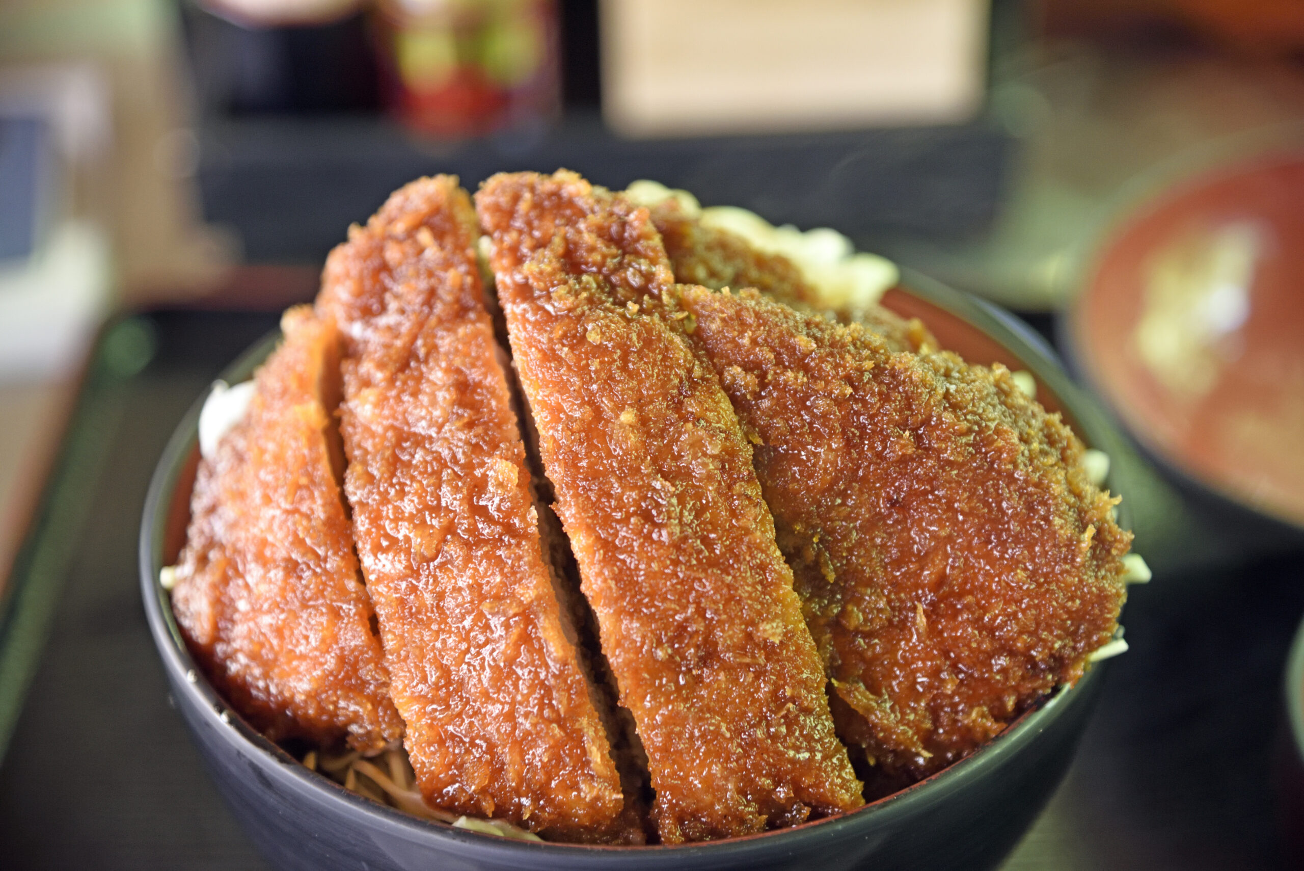 Fried chicken strips stacked in a bowl over noodles, crispy golden-brown crust visible.