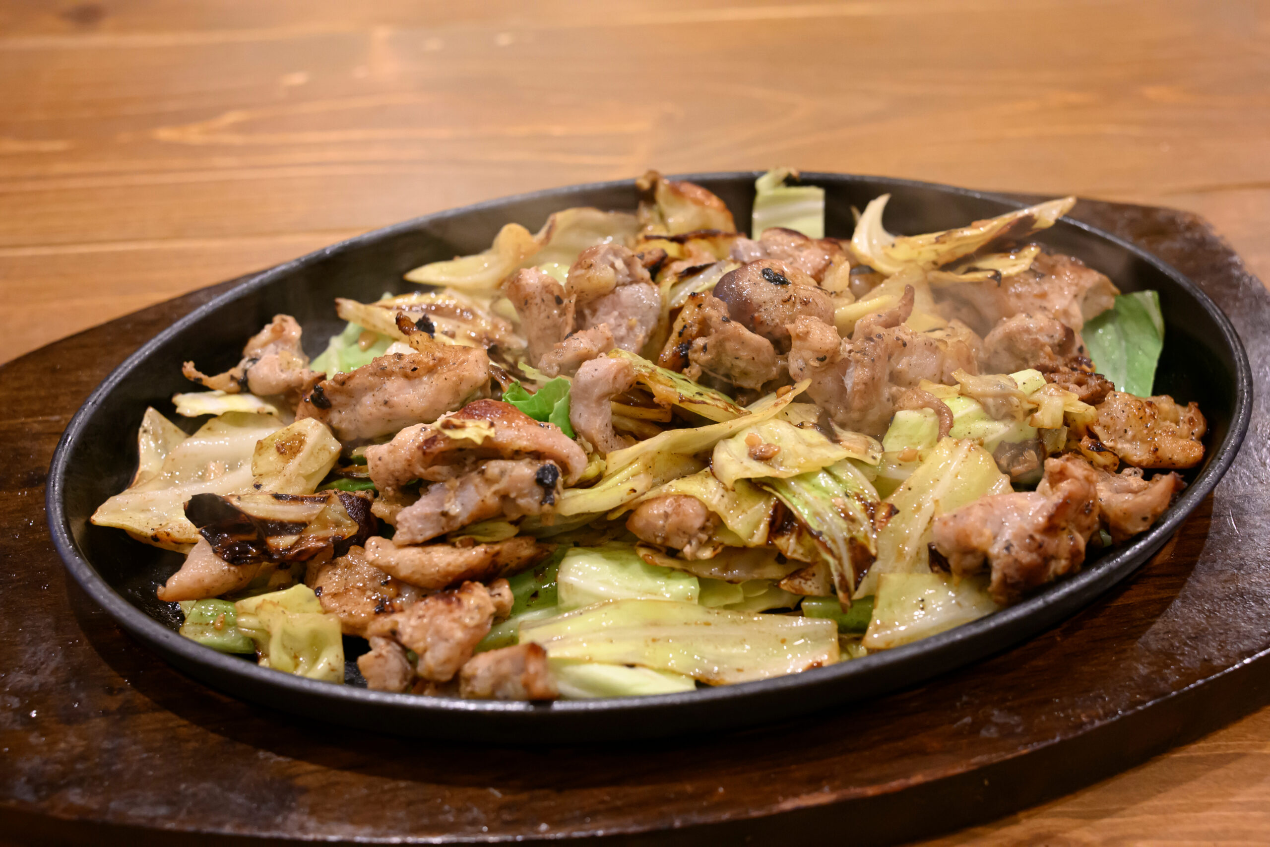 Skillet of sautéed pork with cabbage and onions on a wooden table