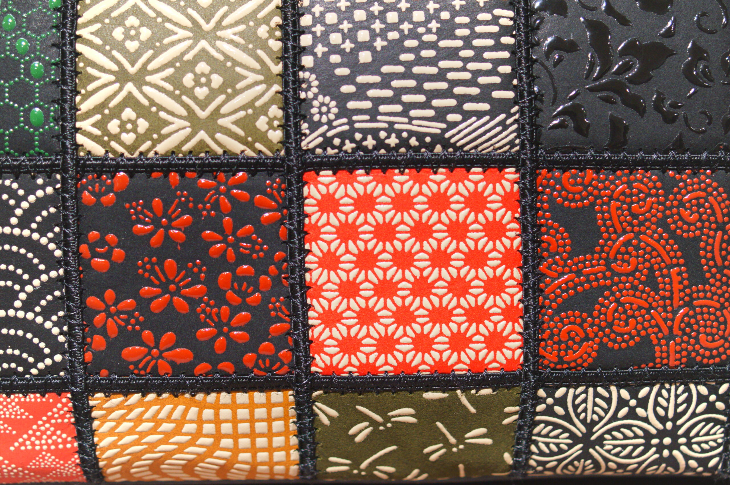 Close-up of a patchwork quilt with colorful patterned fabric squares separated by black stitched seams.