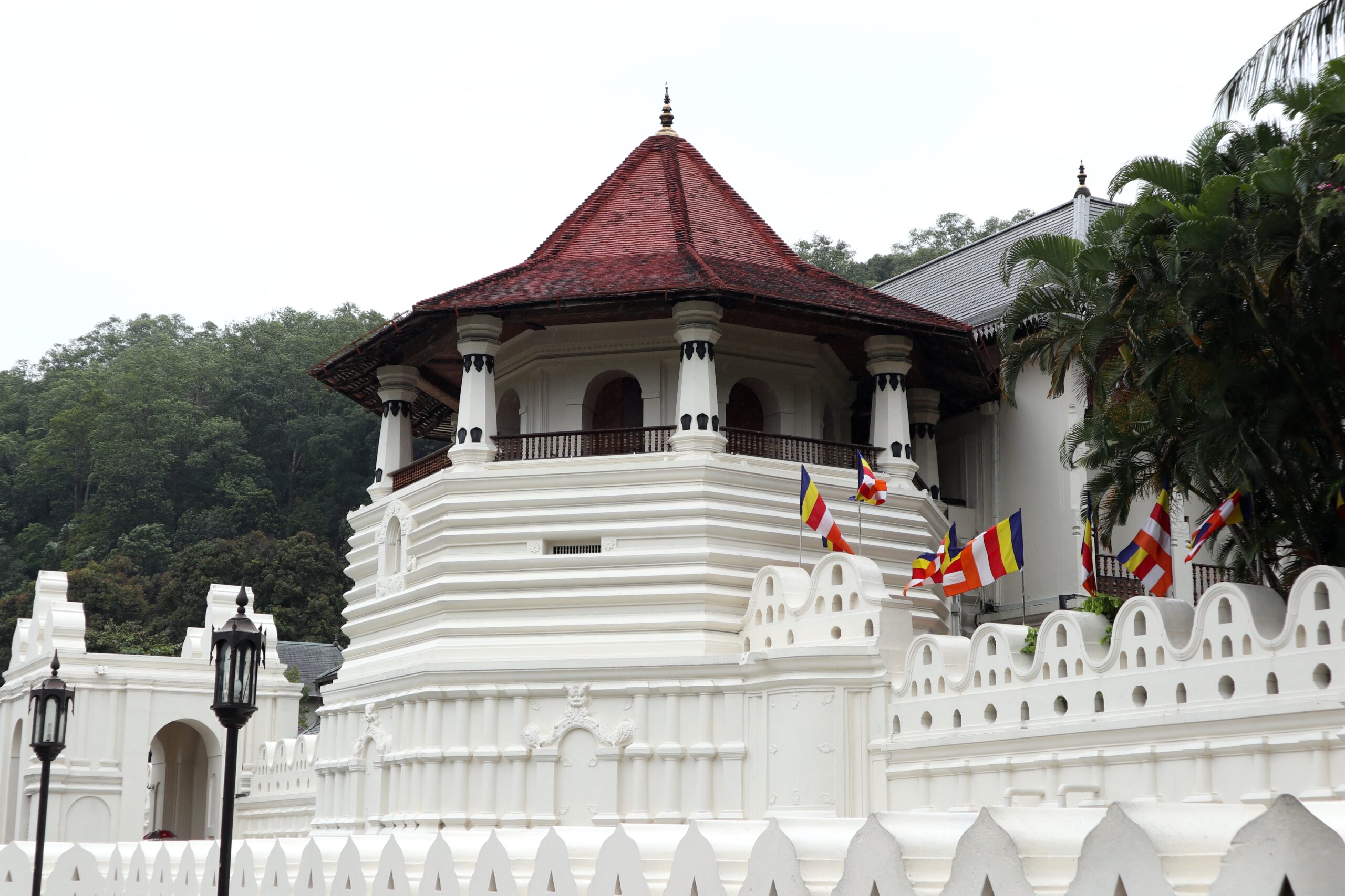 White temple building with a red, pyramid-shaped roof and decorative columns atop a two-story base.