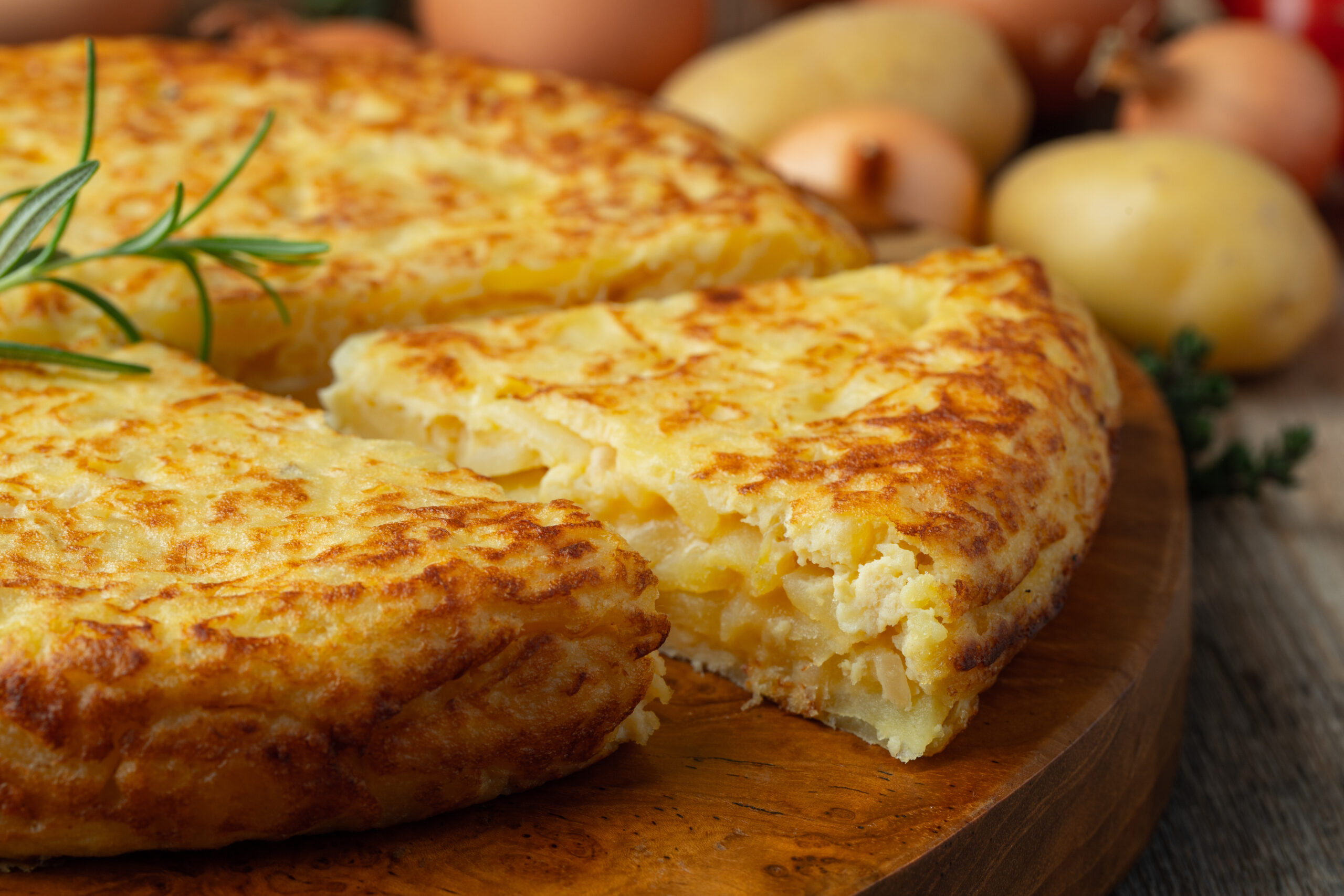 Golden-brown cheesy potato cakes on a wooden platter, garnished with rosemary.