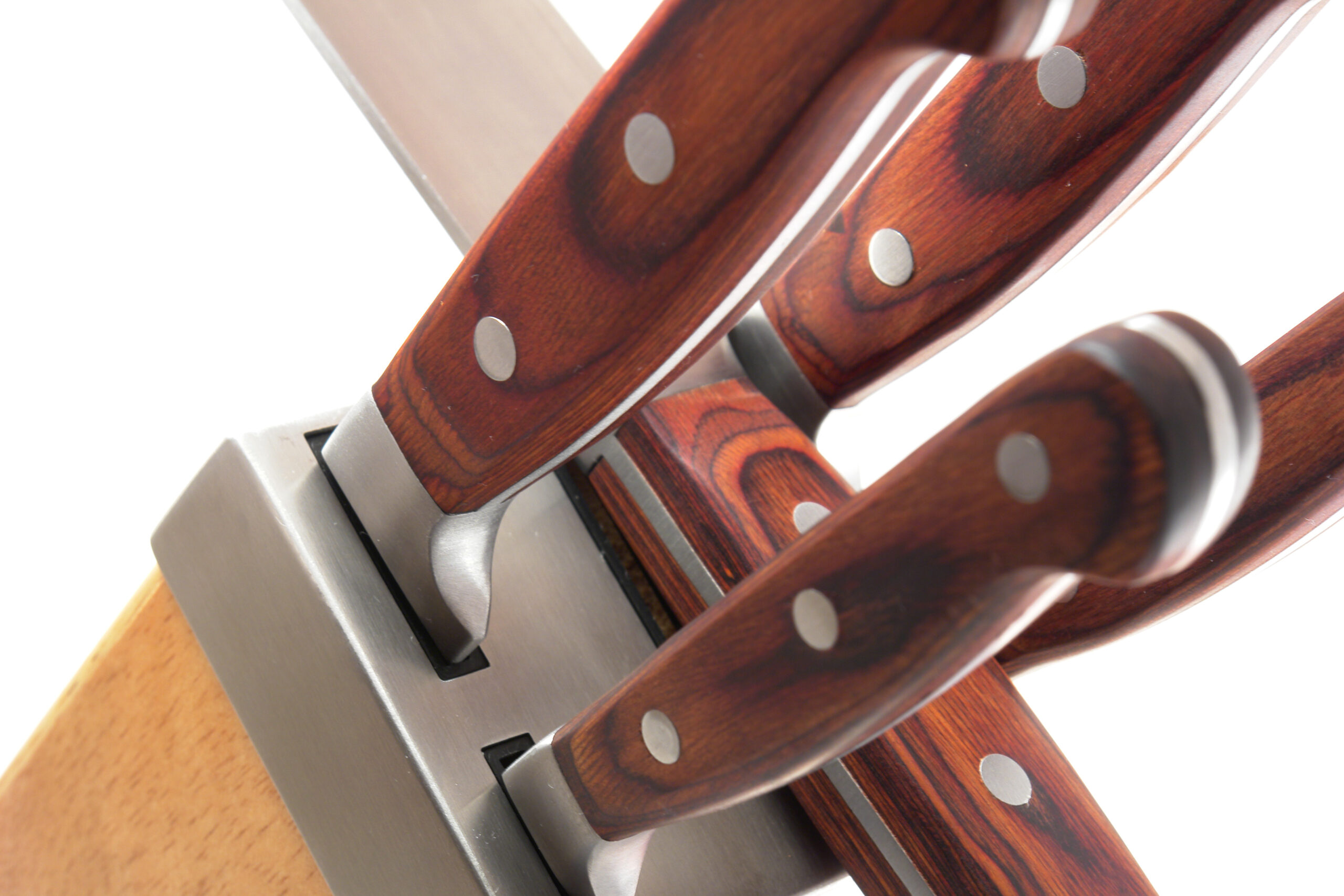 Close-up of multiple wooden-handled kitchen knives with silver rivets and metal blades stacked diagonally.