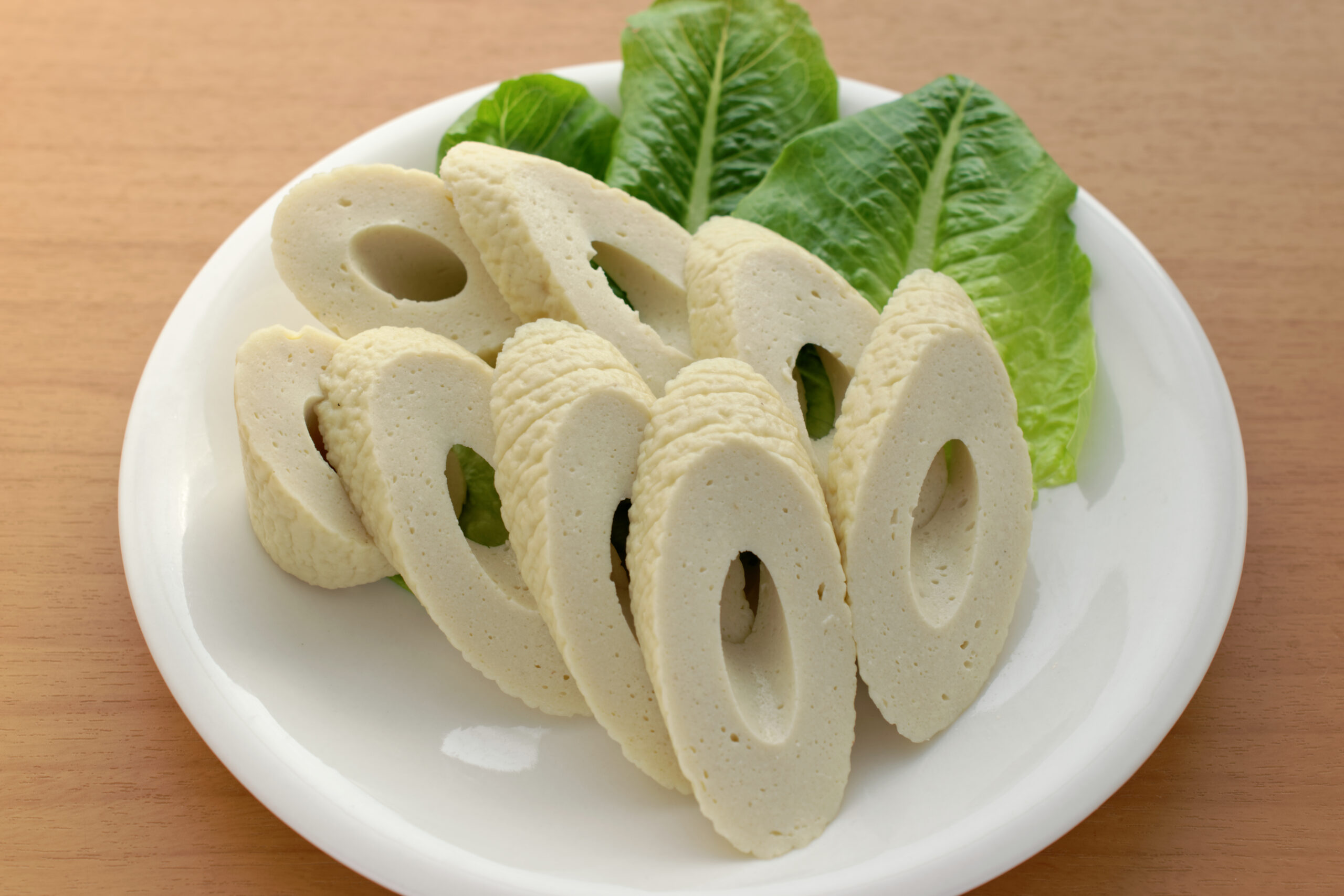 Plate of pale, ring-shaped slices arranged on a bed of green lettuce on a white plate.