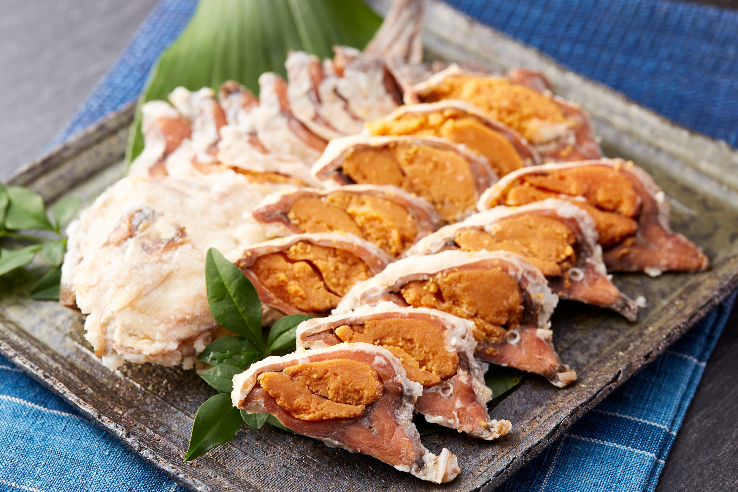 Sliced roasted meat with orange stuffing on a wooden platter, garnished with green herbs.