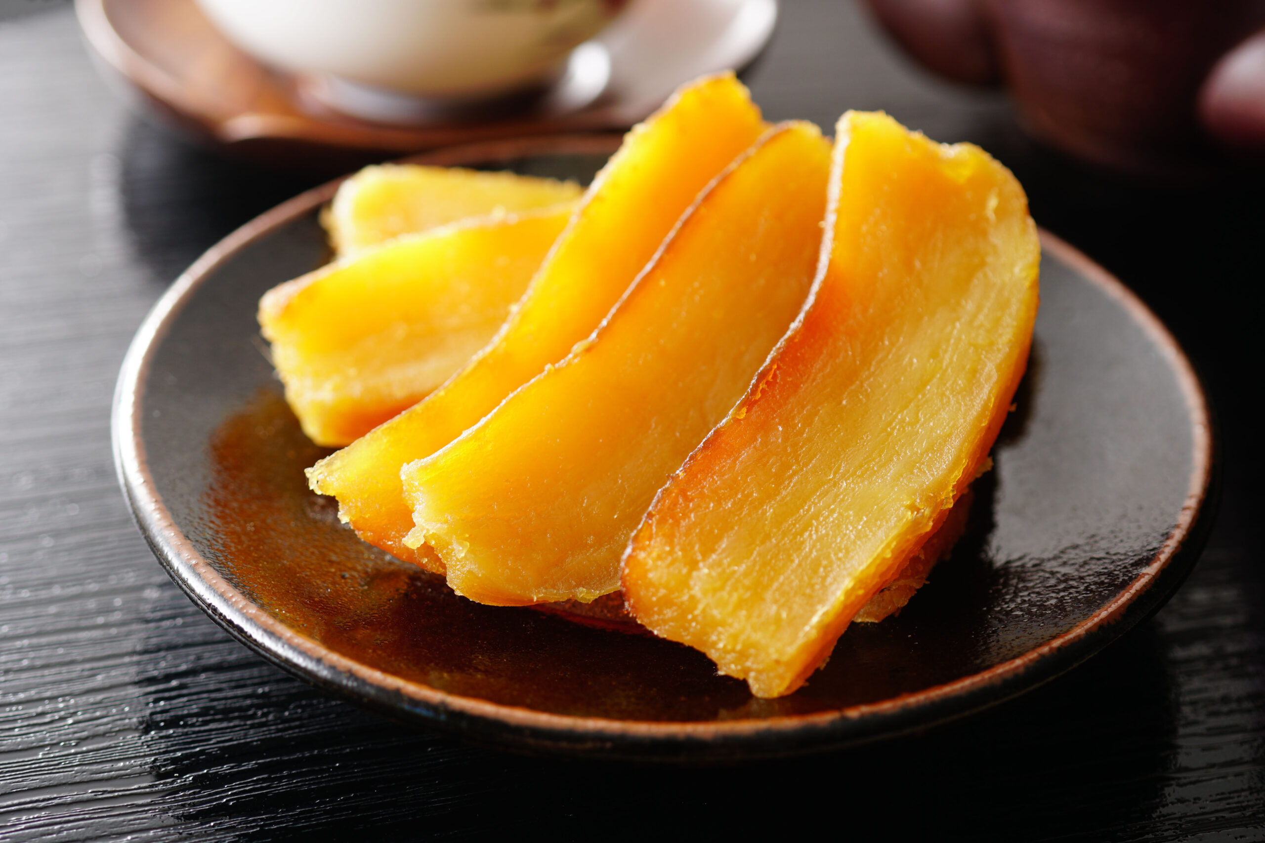 Orange slices arranged on a dark ceramic plate, close-up view showing bright, juicy flesh like wedges ready to eat.