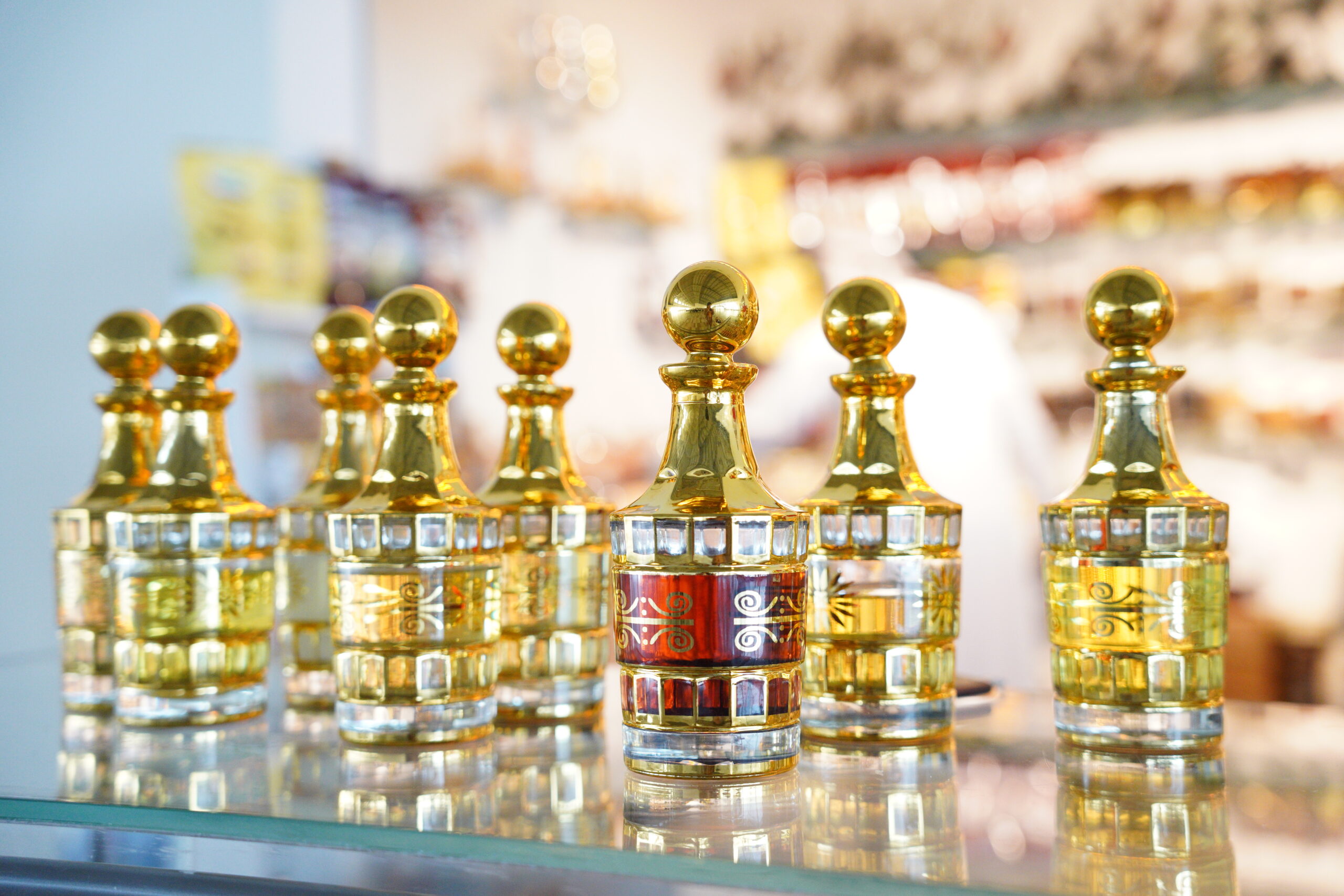 Row of shiny gold chess king pieces lined up on a glass display shelf with reflections visible in the foreground.