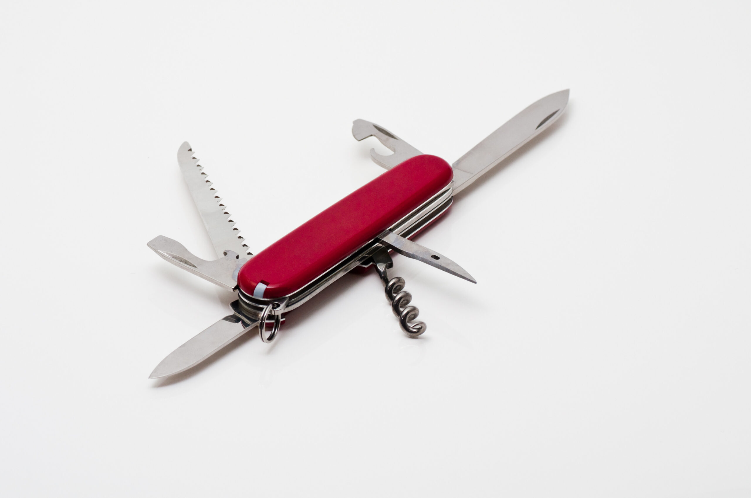 Red Swiss Army knife with blades, saw, and corkscrew extended on a white background, viewed from above.