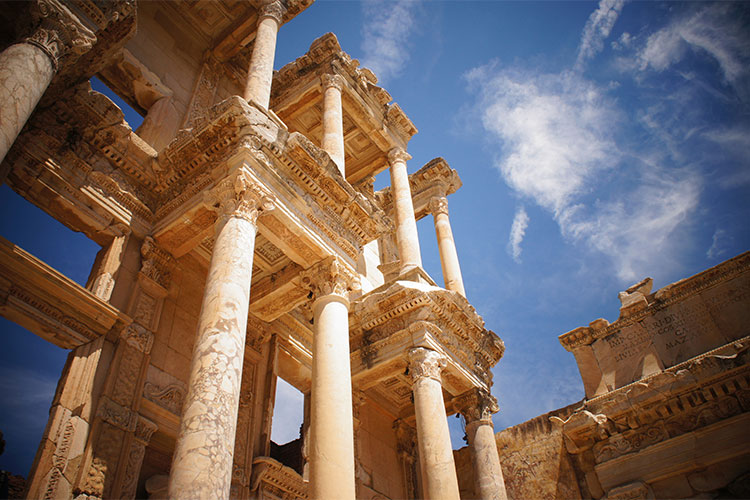 Ancient ruin with tall marble columns and intricate stonework against a blue sky