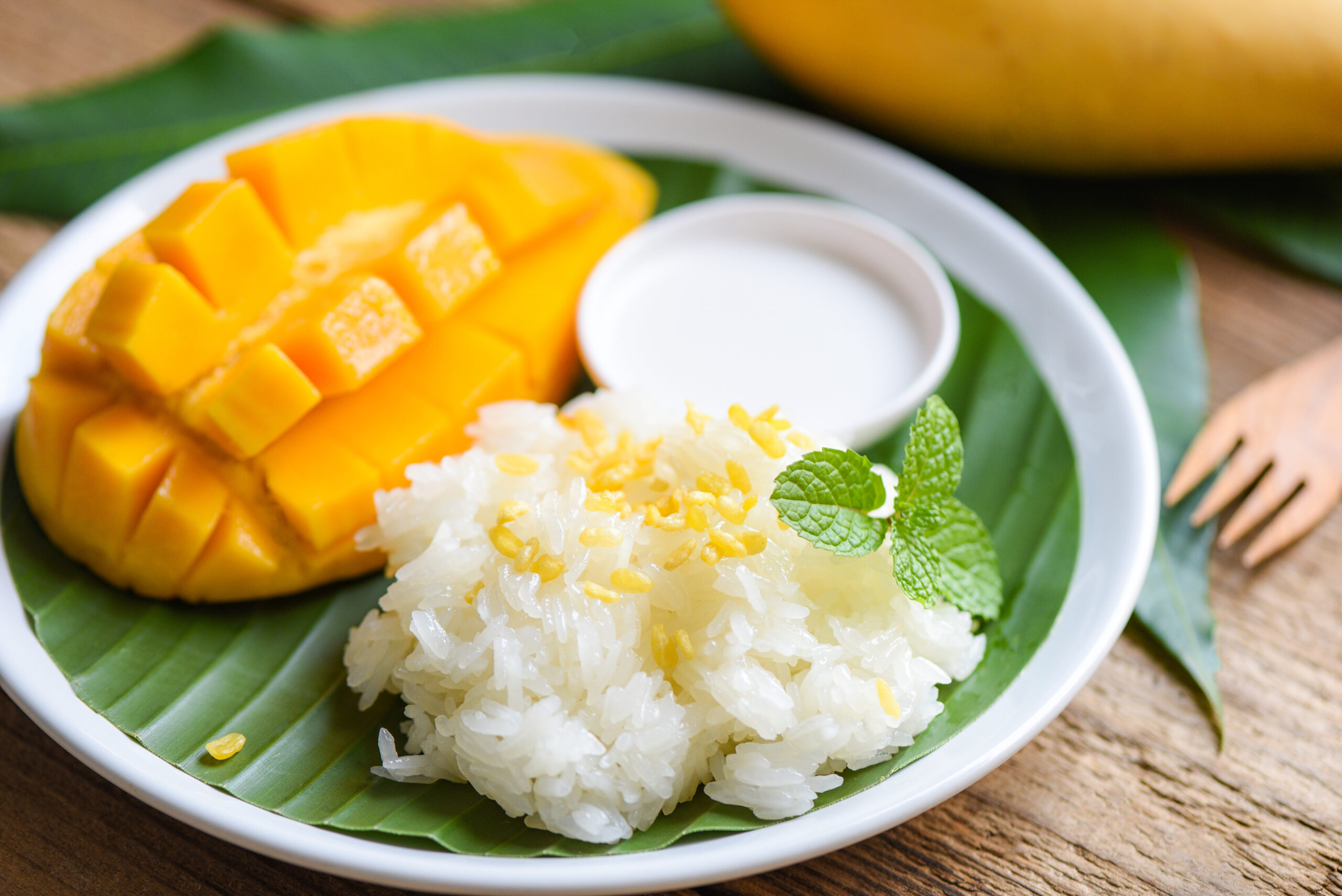 Thai mango sticky rice: ripe mango chunks with coconut rice, served on a banana leaf with mint garnish