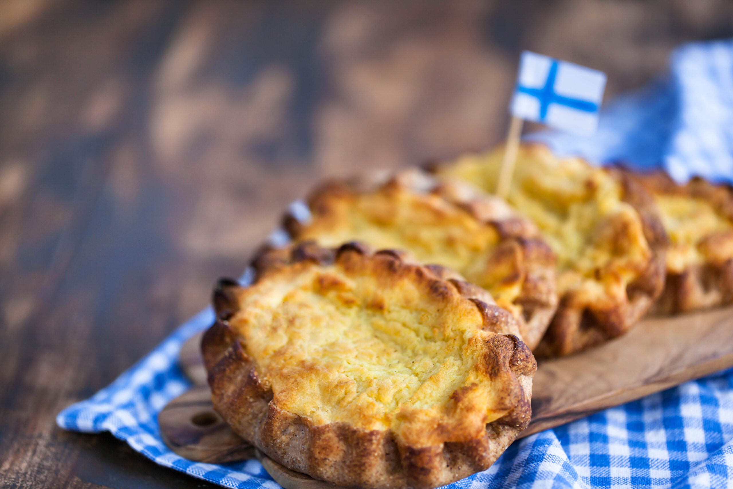 Fresh baked muffins on a wooden board, with a small Finnish flag toothpick on top.