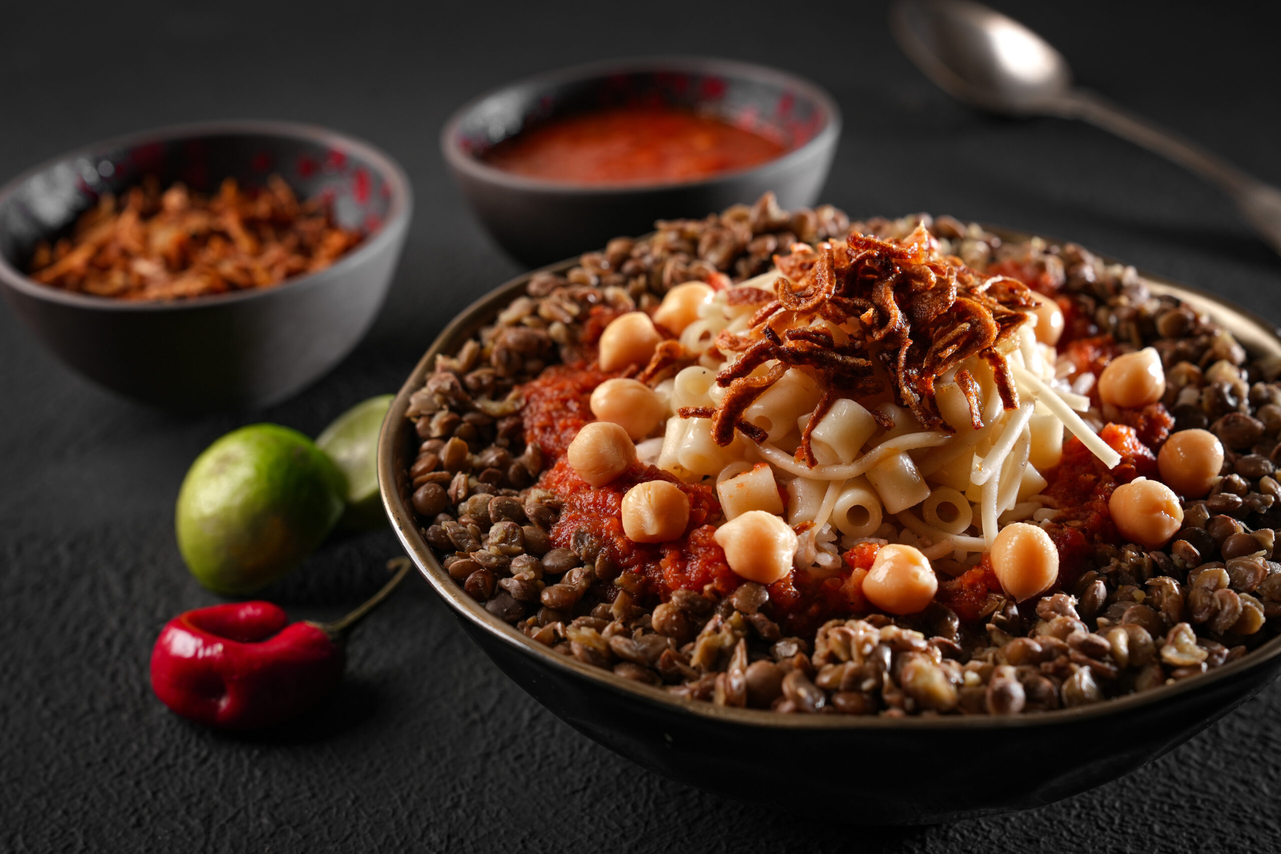 Bowl of pasta with tomato sauce, chickpeas, lentils, and crispy fried onions on top.