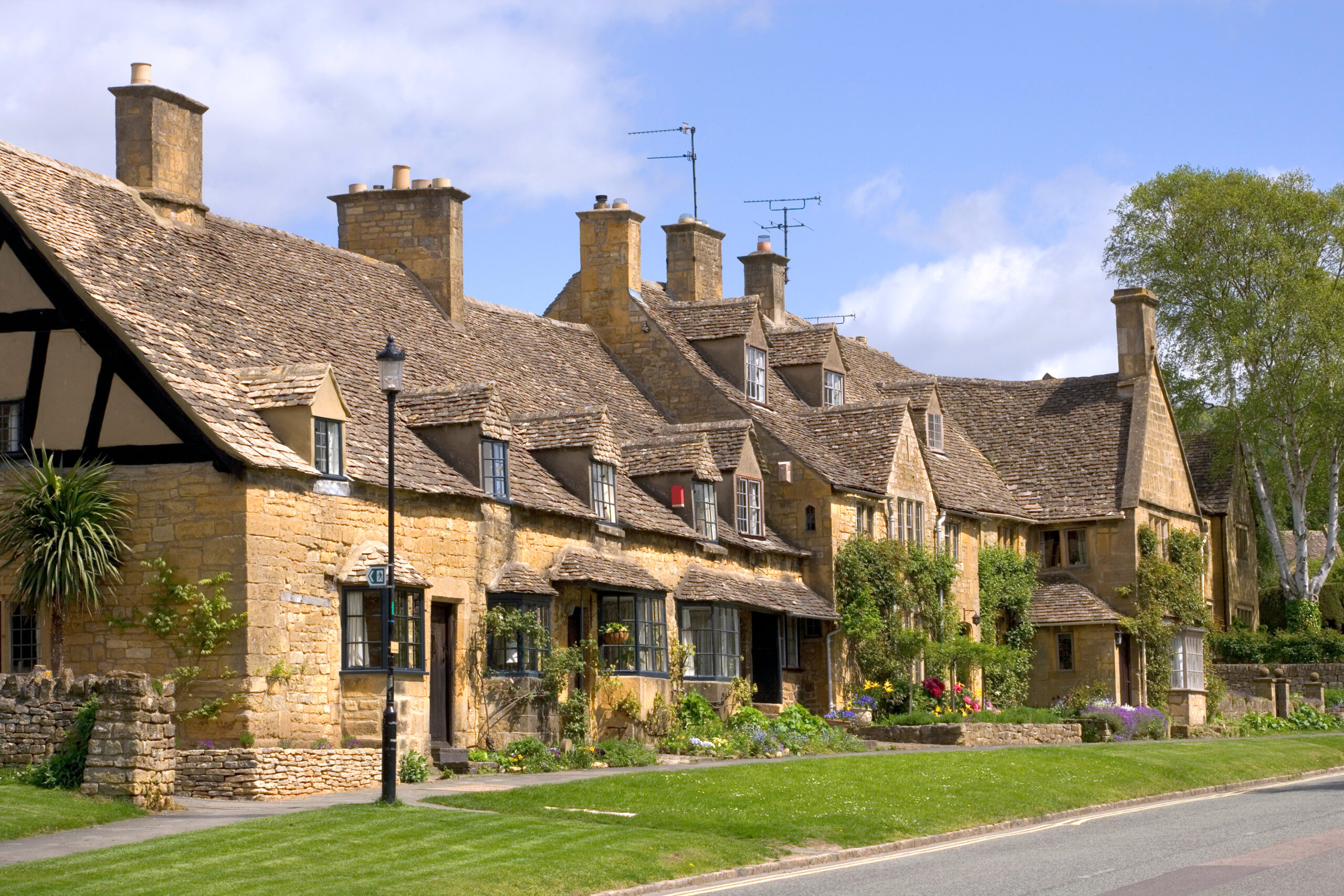 Row of stone cottages with slate roofs and tall chimneys under a blue sky.