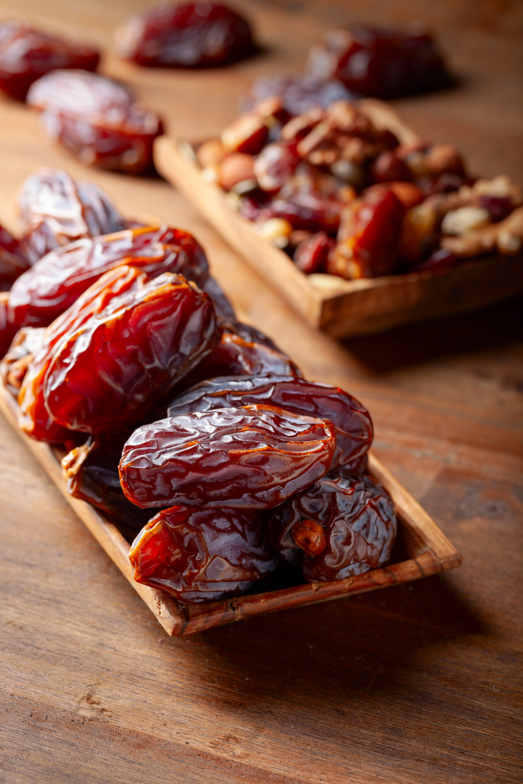 Close-up of glossy, wrinkled dried dates on a wooden surface.