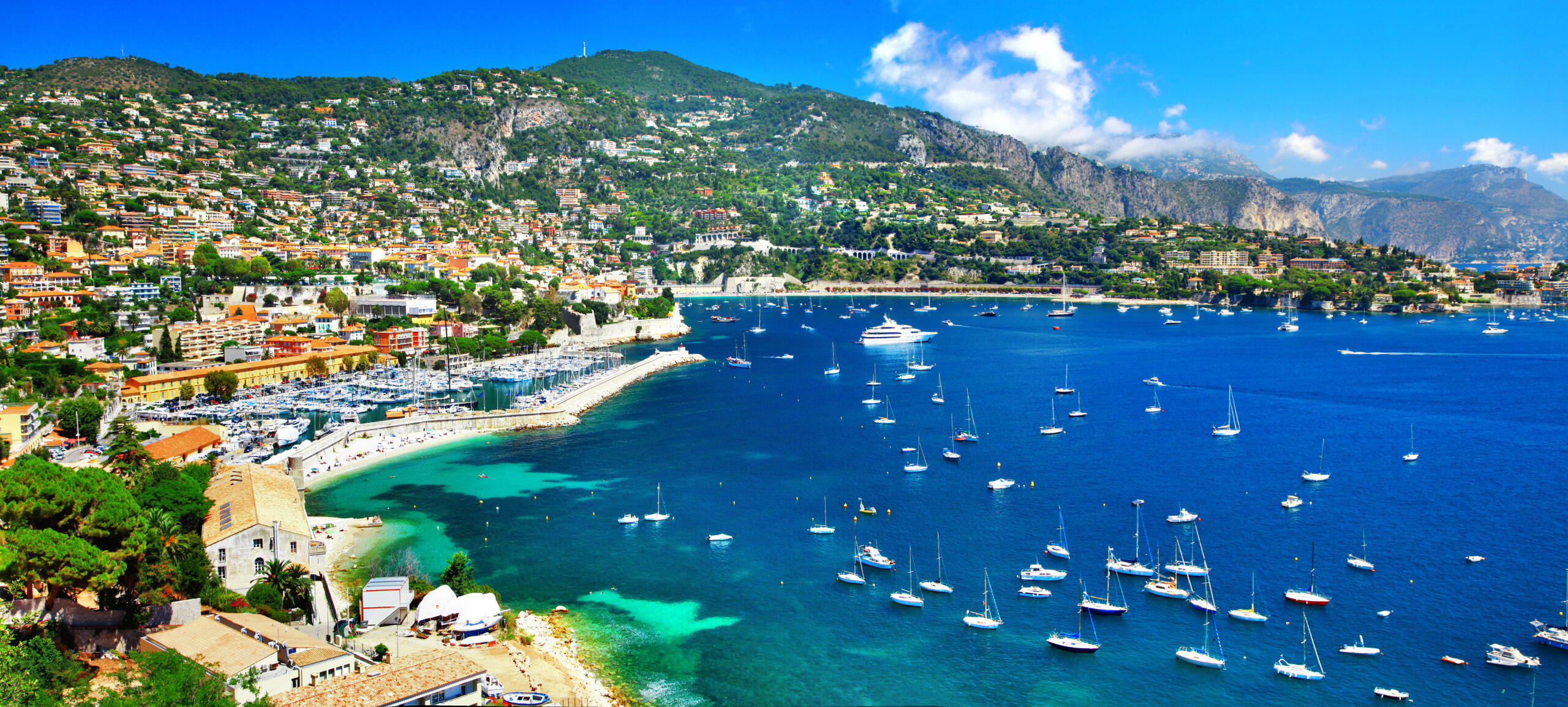 Coastal town built on terraced hillsides with a busy marina and blue bay.