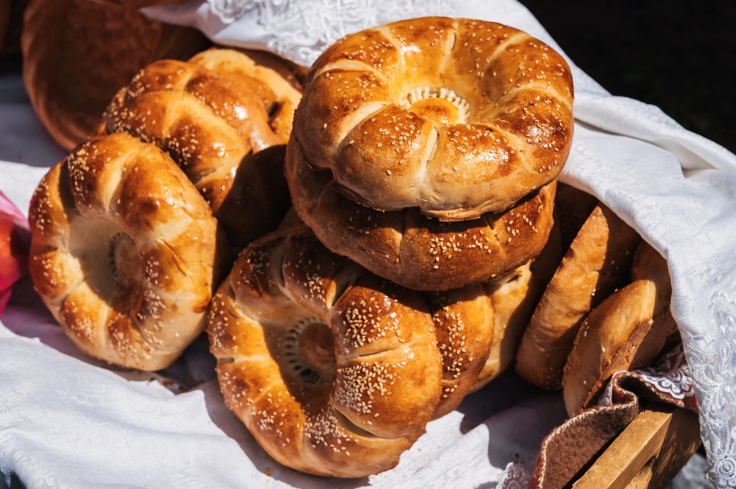 Fresh bagels with sesame seeds stacked on a white cloth, ready to serve.