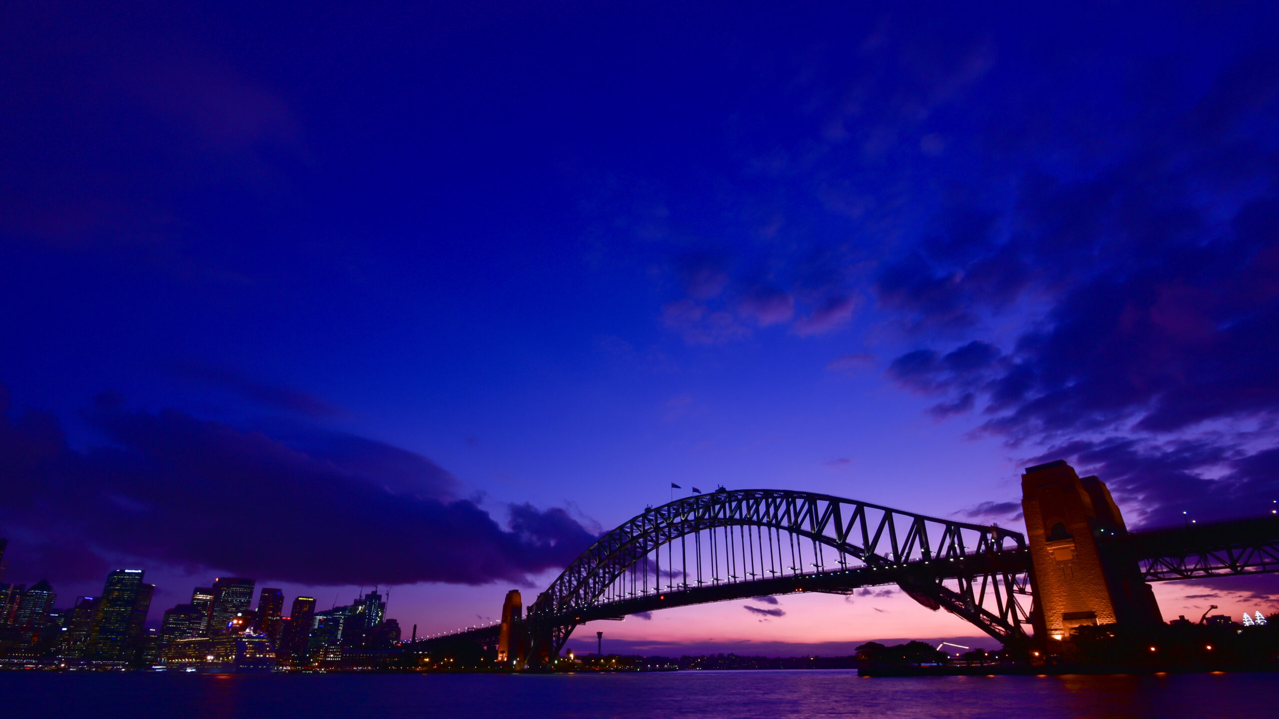 Sydney Harbour Bridge at dusk with the city skyline and a deep blue-purple sky.3a8306