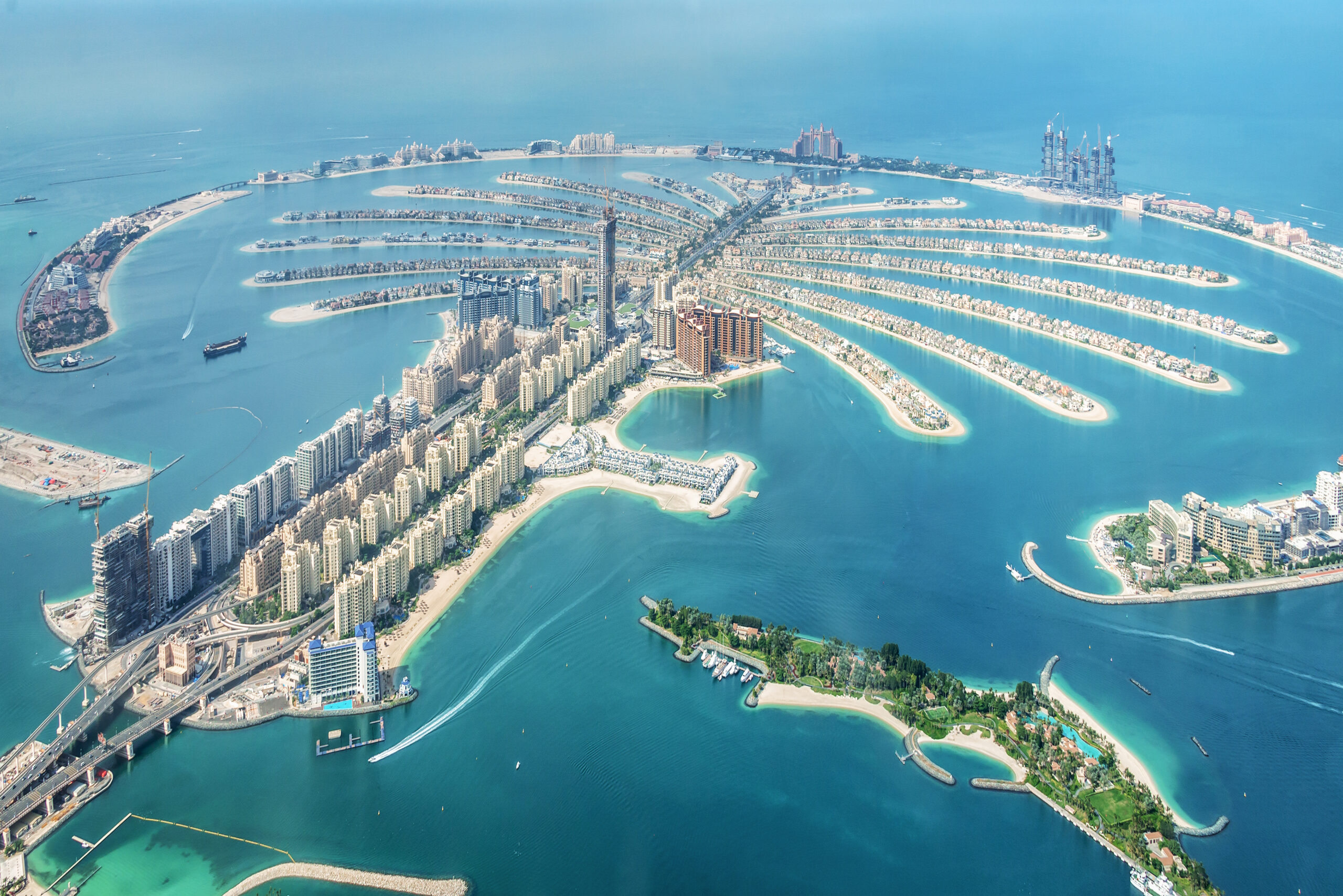 Aerial view of Palm Jumeirah in Dubai: a palm-shaped island with fronds, turquoise water, and surrounding high-rise buildings along the coast.