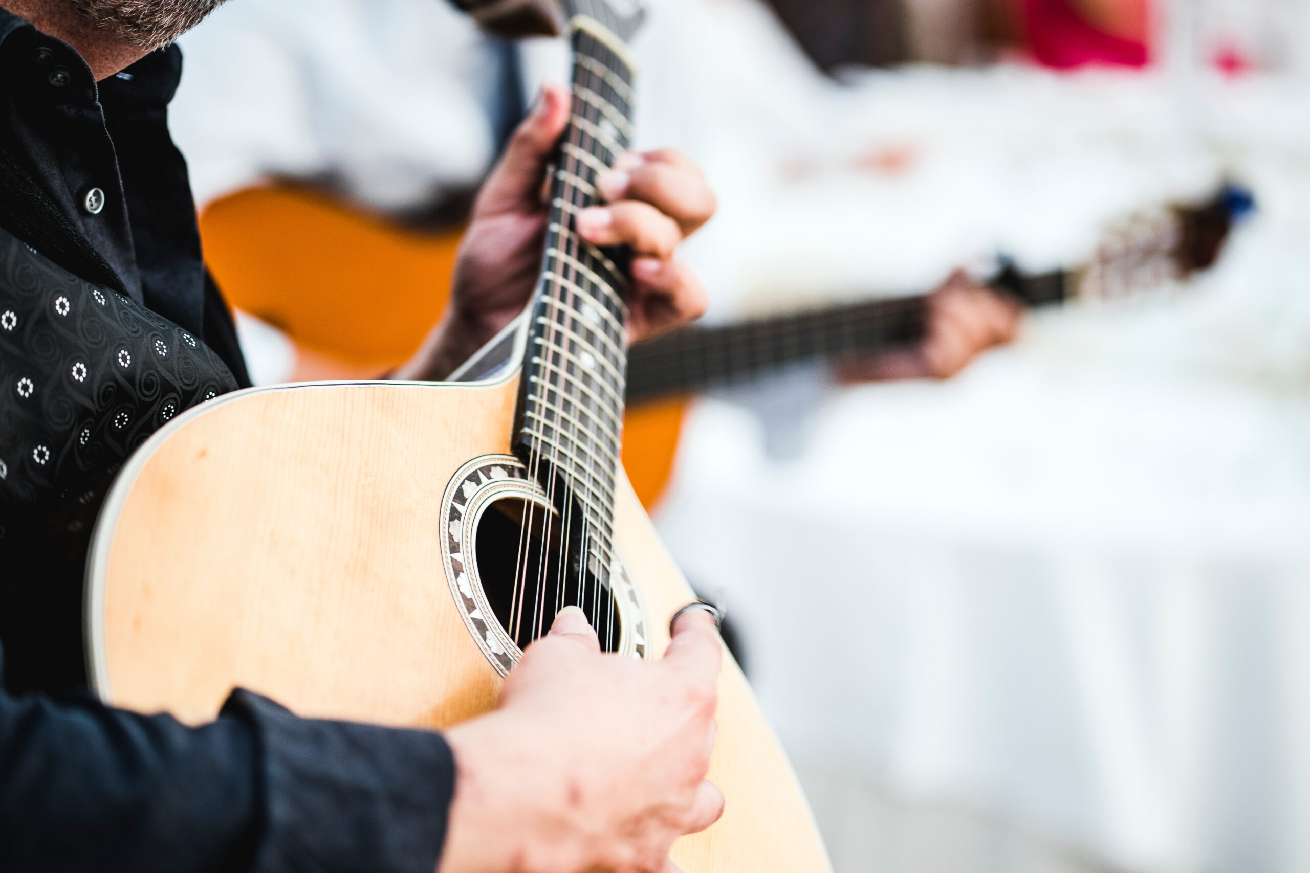 Close-up of hands pressing guitar strings on the fretboard of an acoustic guitar in use
