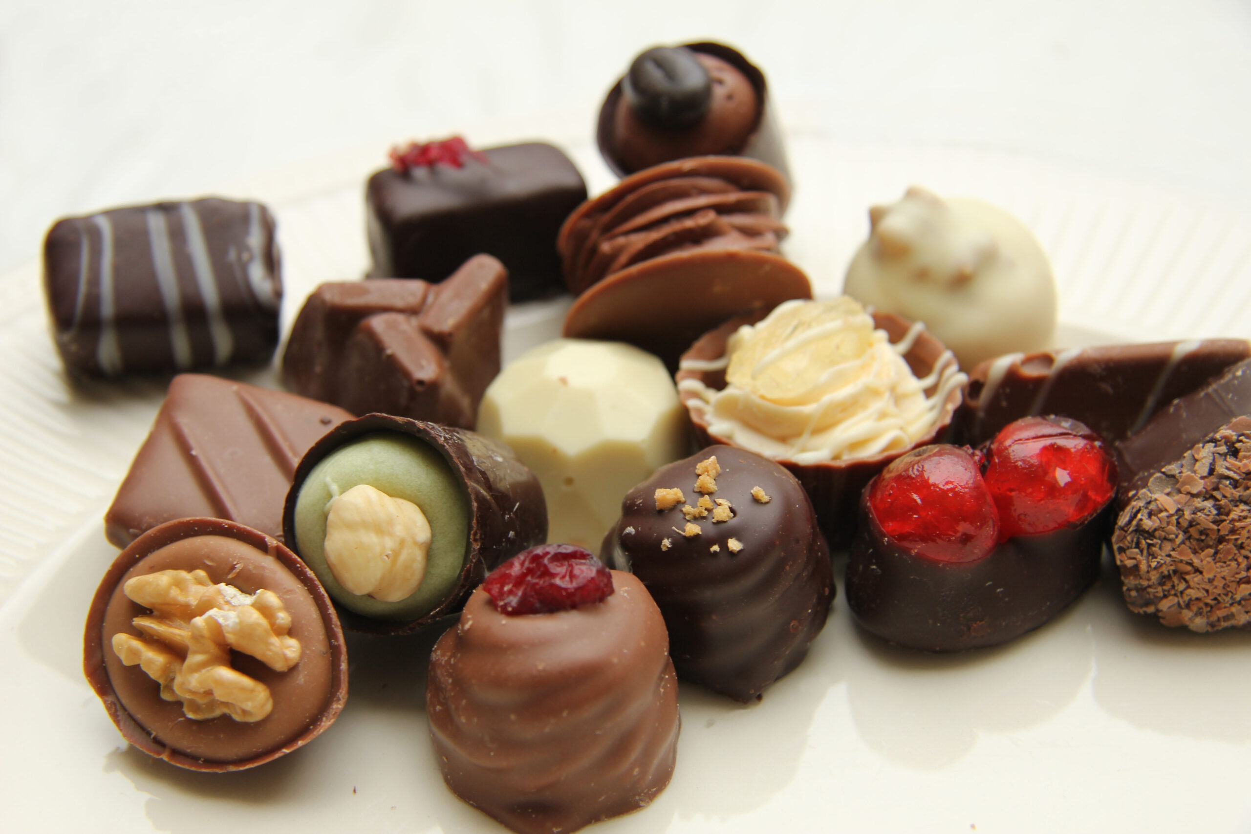 Assorted chocolates and truffles on a white plate, including hazelnut and berry fillings.
