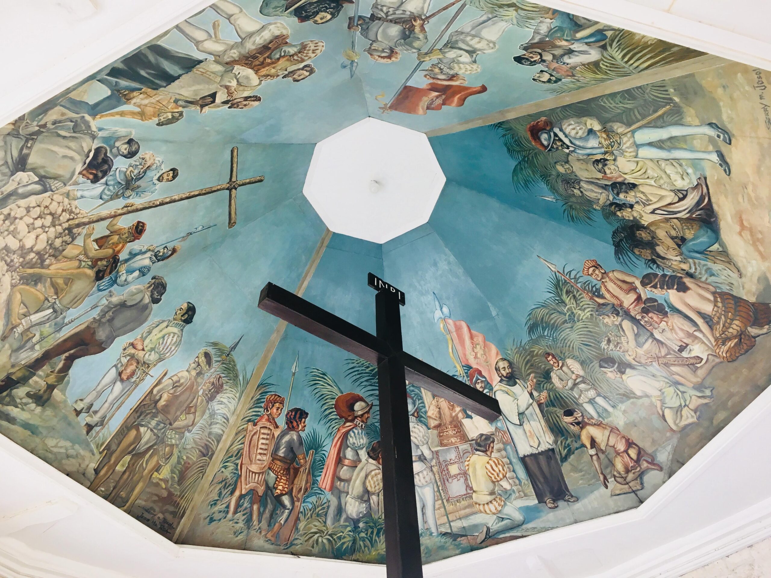 Decorative ceiling mural showing a bustling historic scene with people in period clothing, palm trees, and a central white octagonal opening.