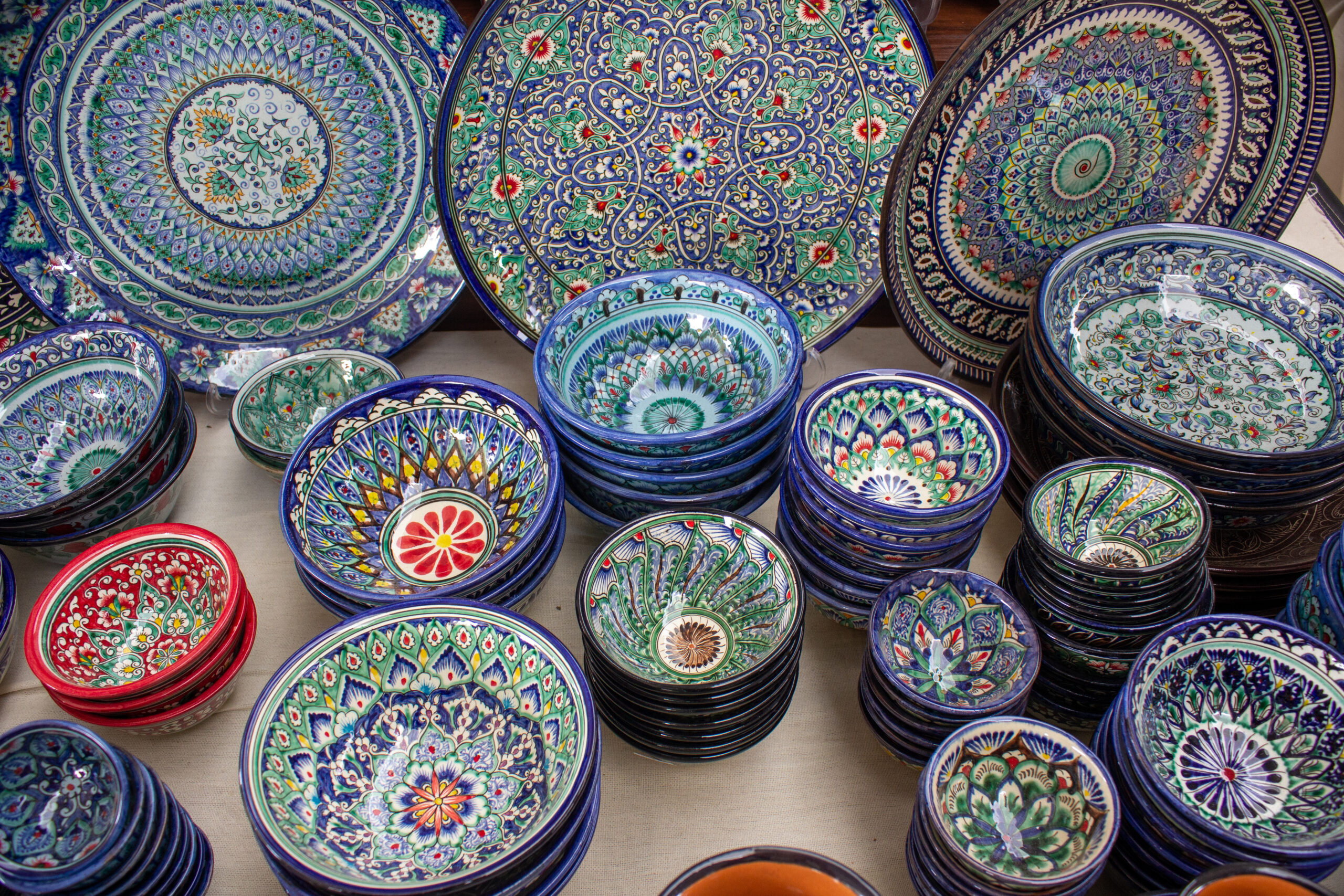 Stacked decorative ceramic plates and bowls with intricate blue, turquoise, and red floral patterns.