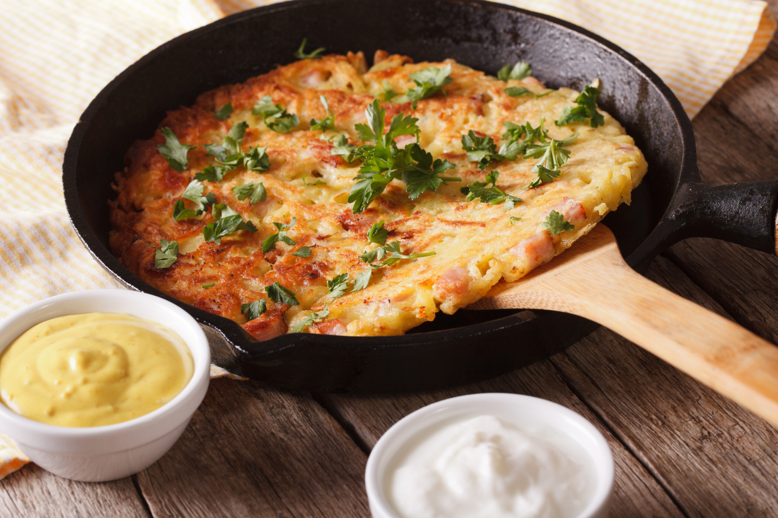 Skillet baked omelette with melted cheese and chopped parsley, served with dipping sauces on the side