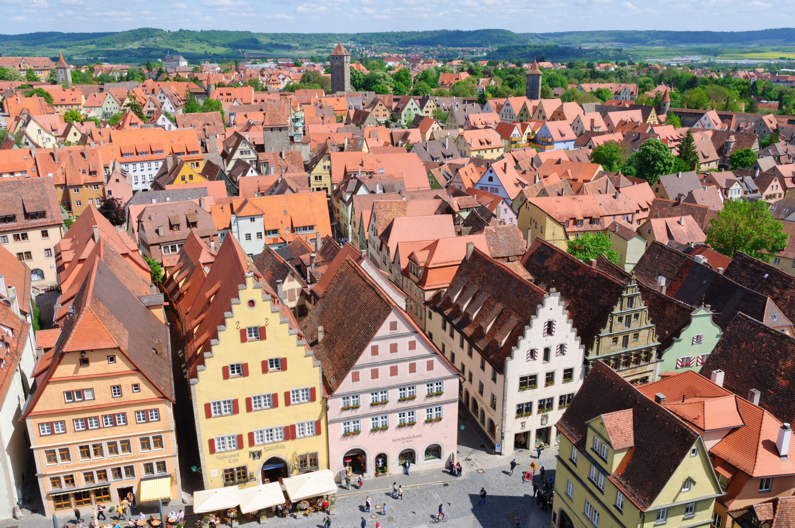 Aerial view of a historic European town with colorful red-tiled roofs and narrow streets.