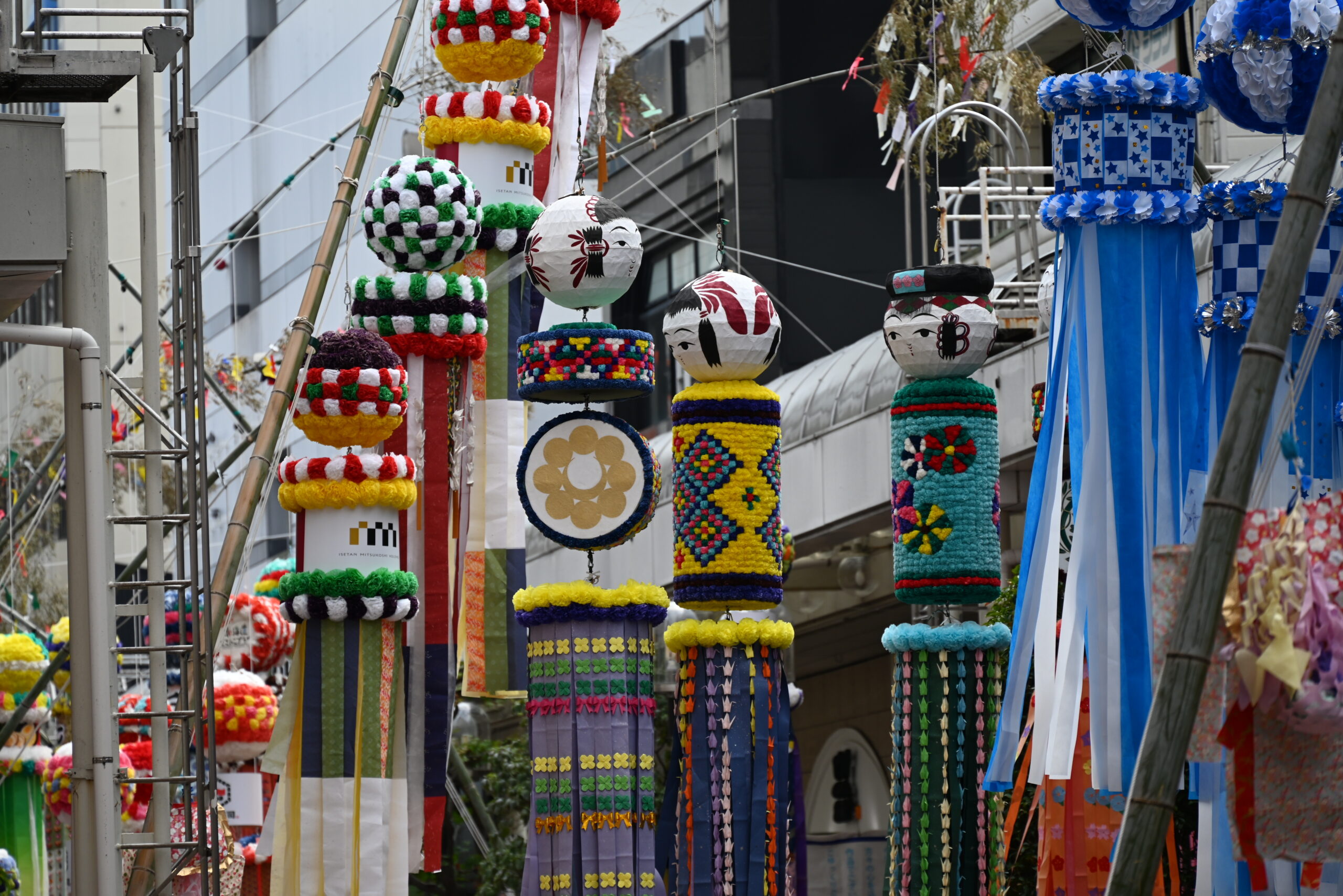 Colorful festival lanterns and tassel decorations hanging along a city street.