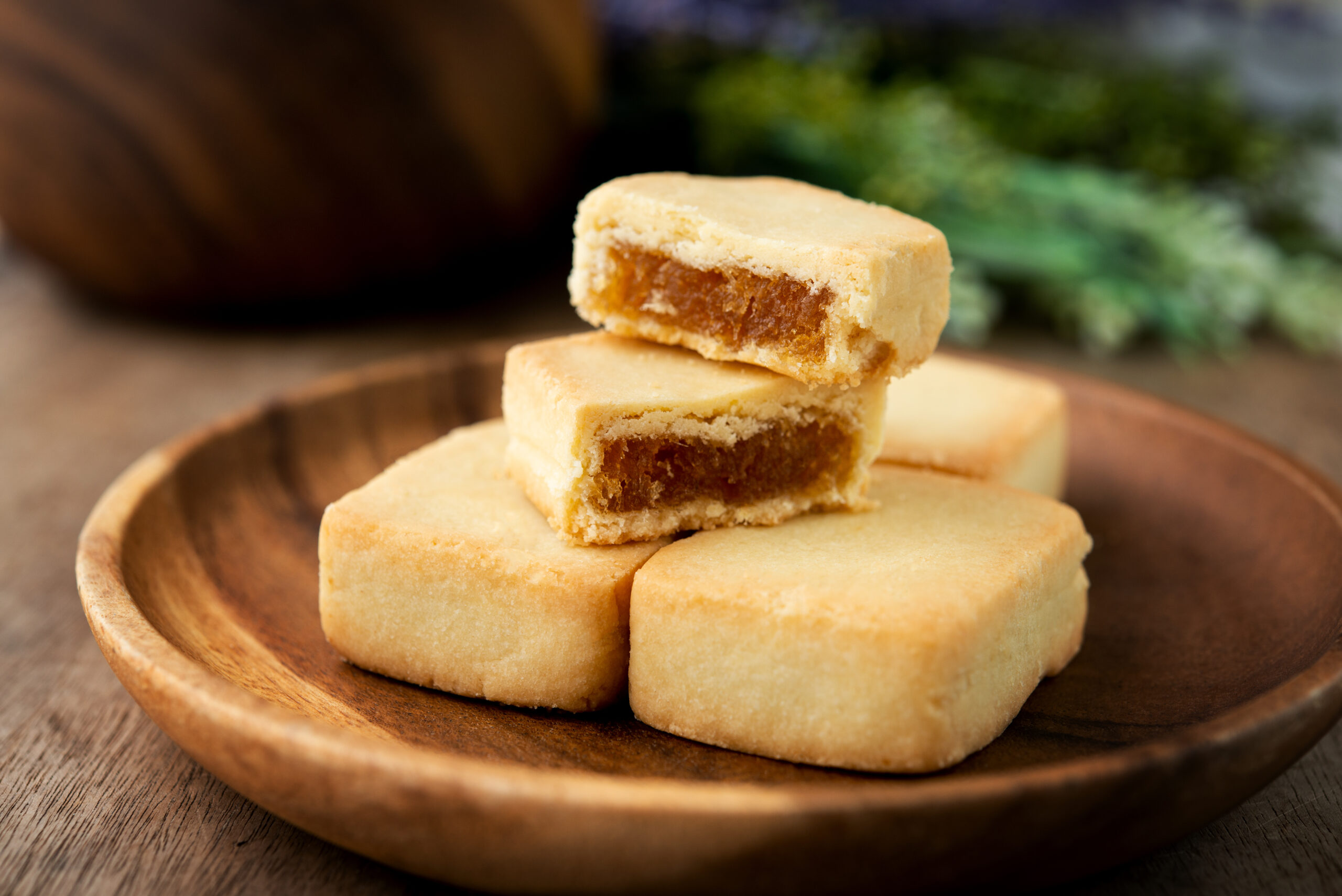 Stack of rectangular sandwich cookies with a brown filling on a wooden plate