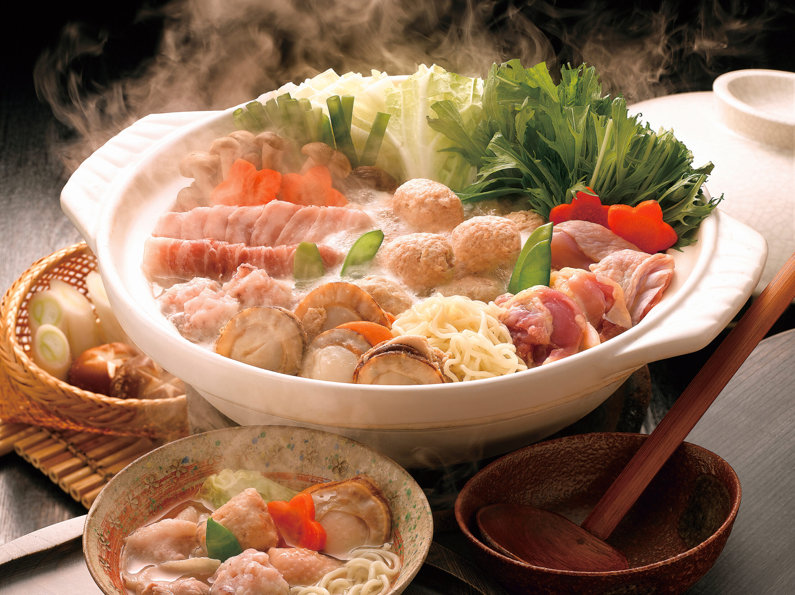 Hot pot filled with steaming broth, leafy greens, mushrooms, meat slices, meatballs, carrots, and noodles.
