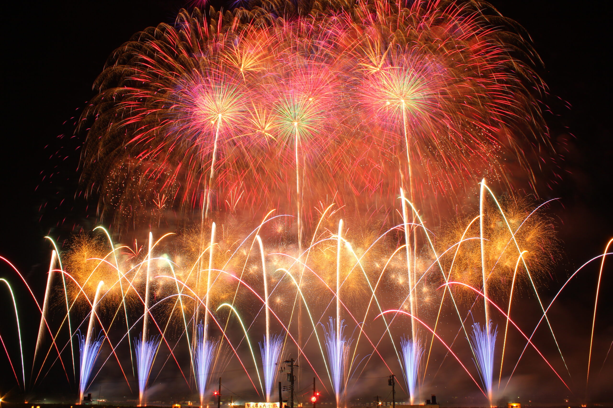 Nighttime fireworks show with colorful bursts illuminating the sky and rocket trails.