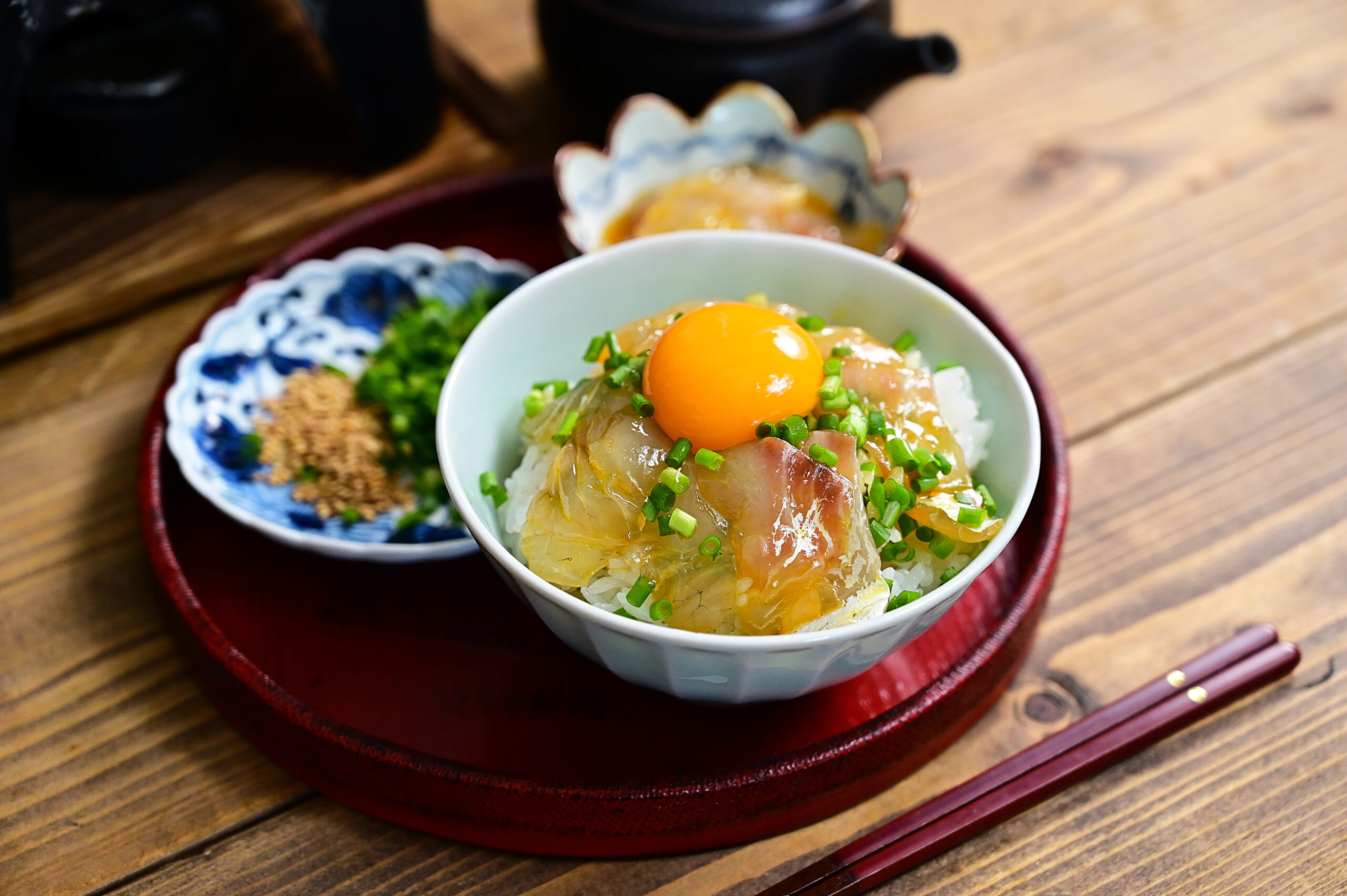 Chirashi donburi: bowl of rice topped with sashimi slices, an orange egg yolk, and chopped chives.