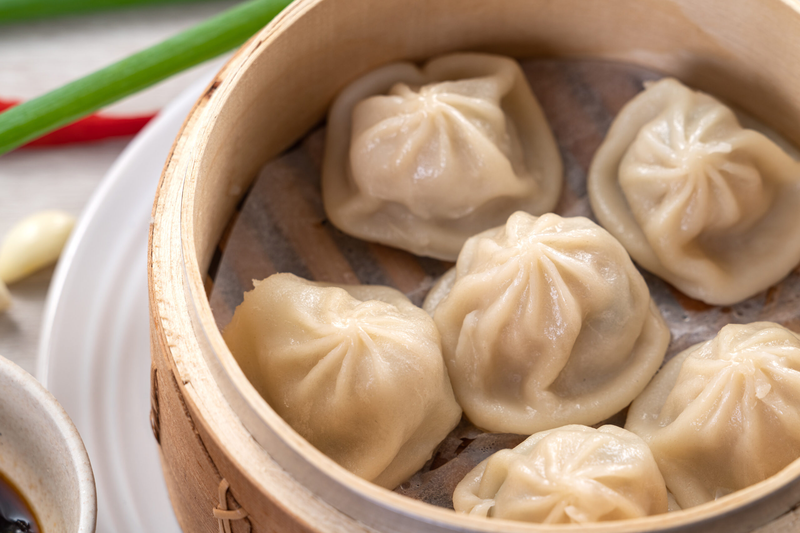 Xiao long bao dumplings steamed in a round bamboo basket