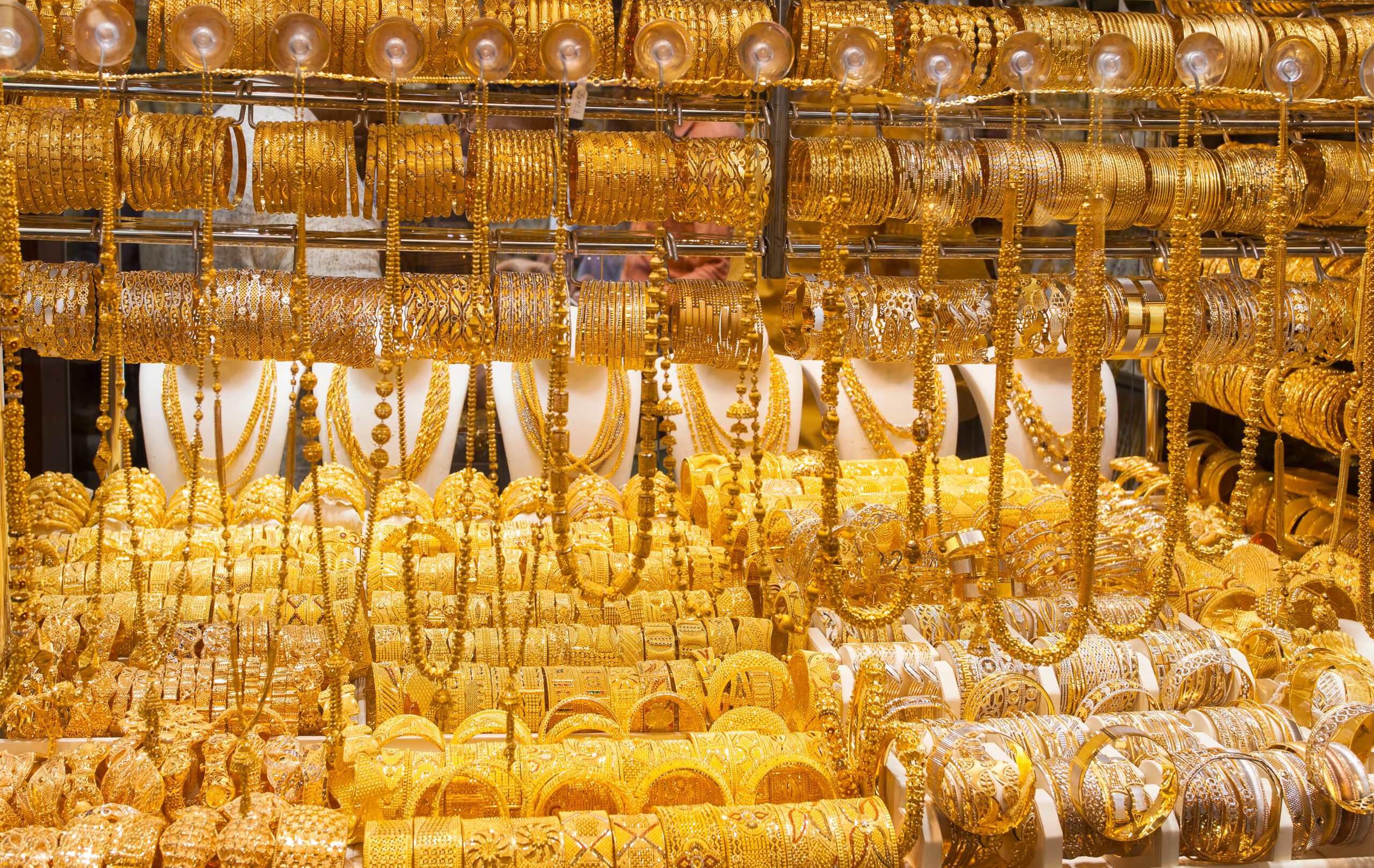 Rows of gold bangles and bracelets on display in a jewelry shop.