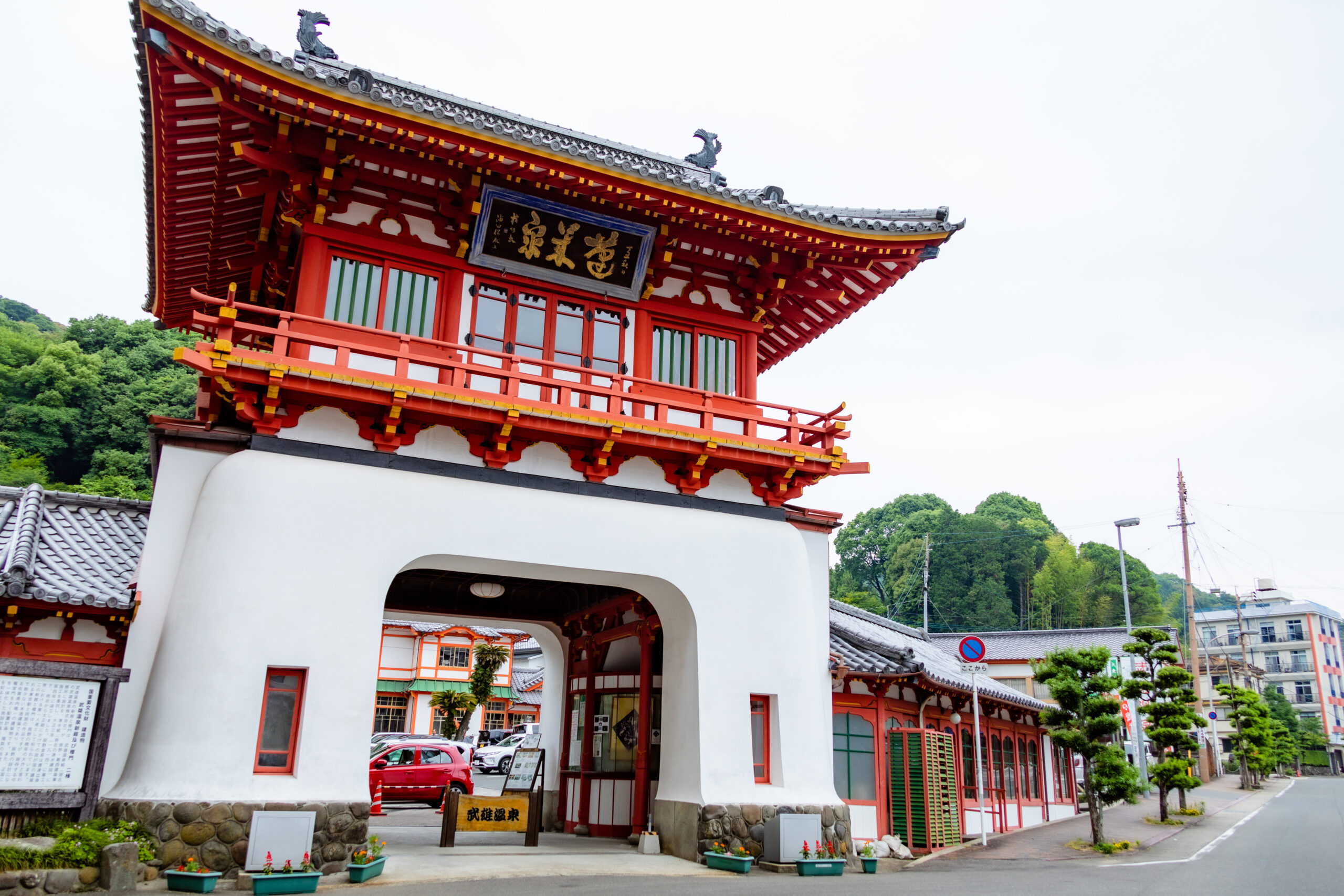Red ornate temple gate with a curved roof and gold accents, opening into a courtyard.