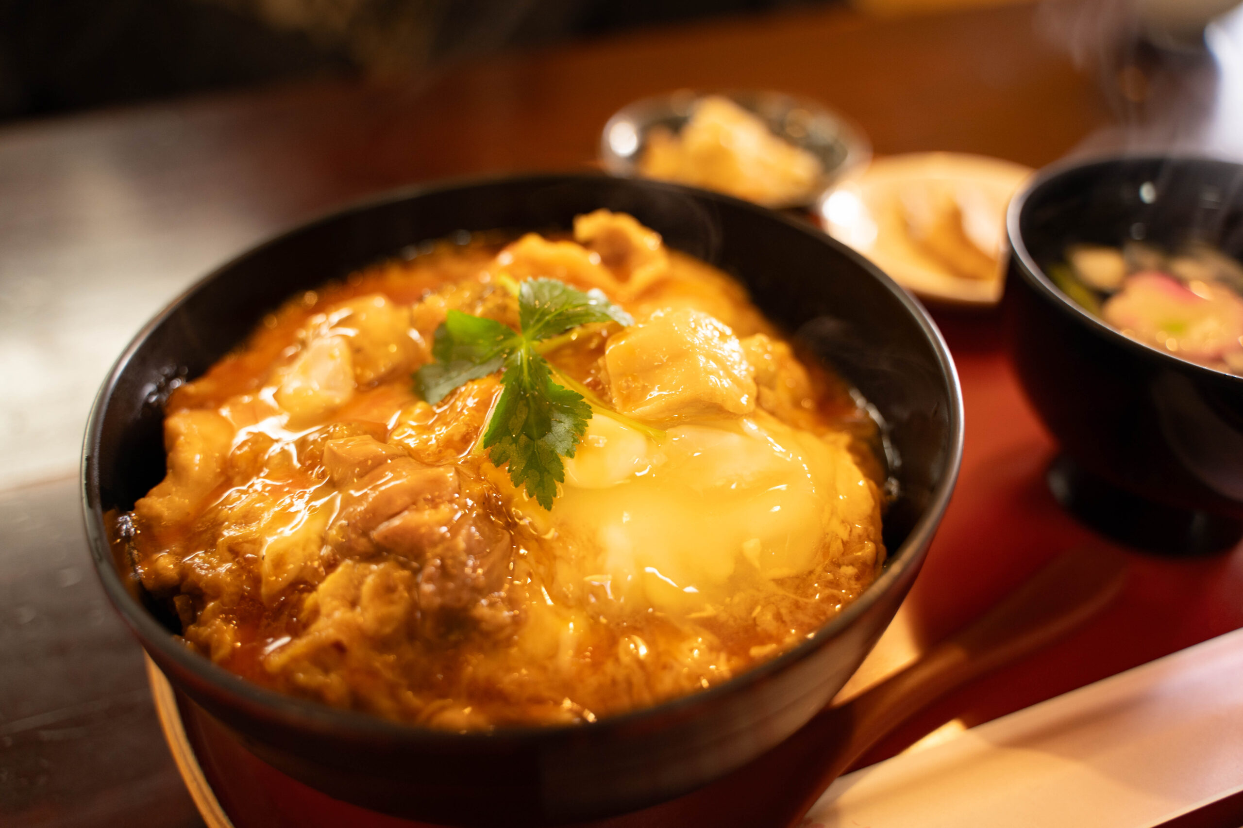 Bowl of beef curry with potatoes and a cilantro garnish, steaming on a table.