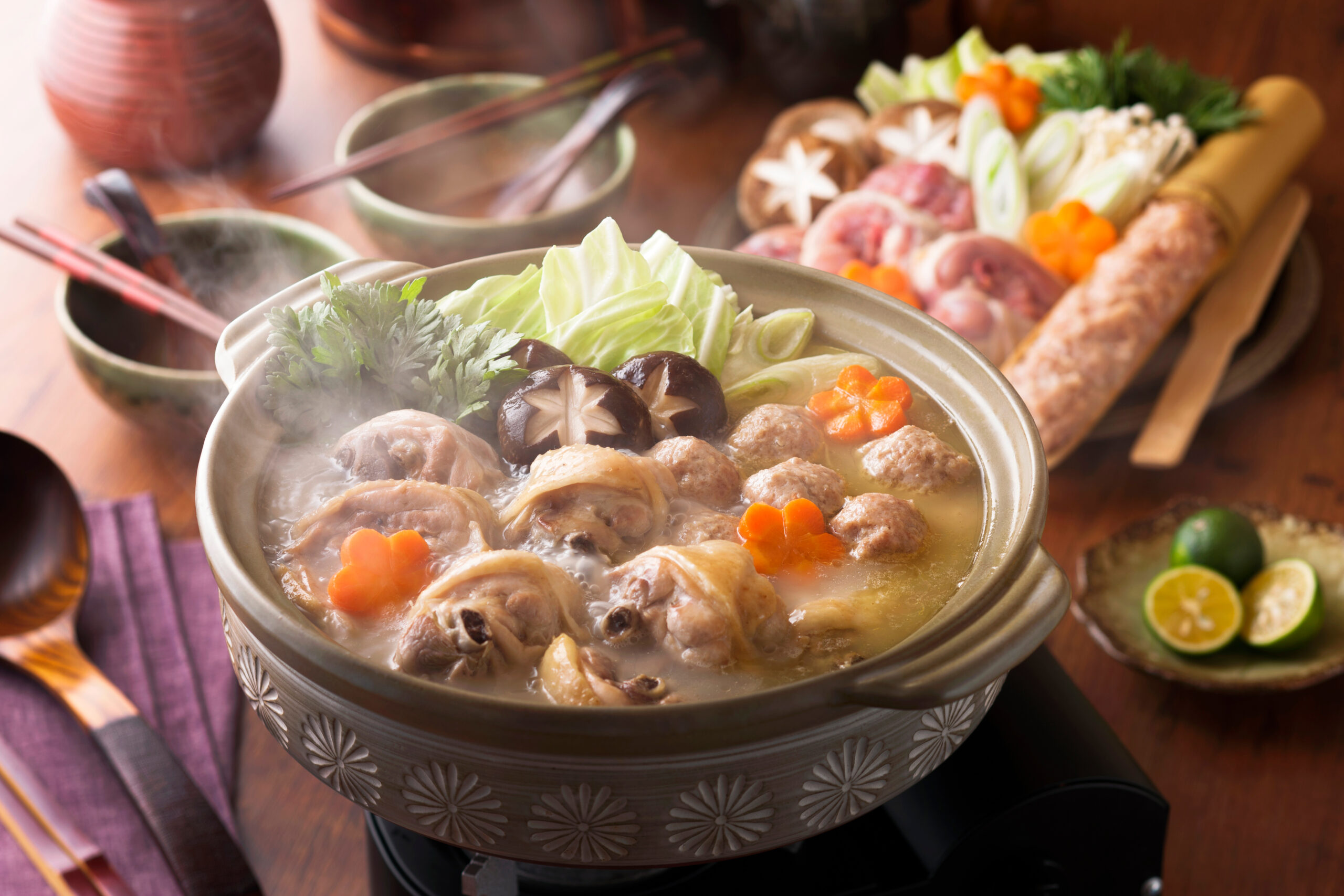 Hot pot filled with meat, mushrooms, cabbage, and carrot flowers, steam rising from a decorative bowl.
