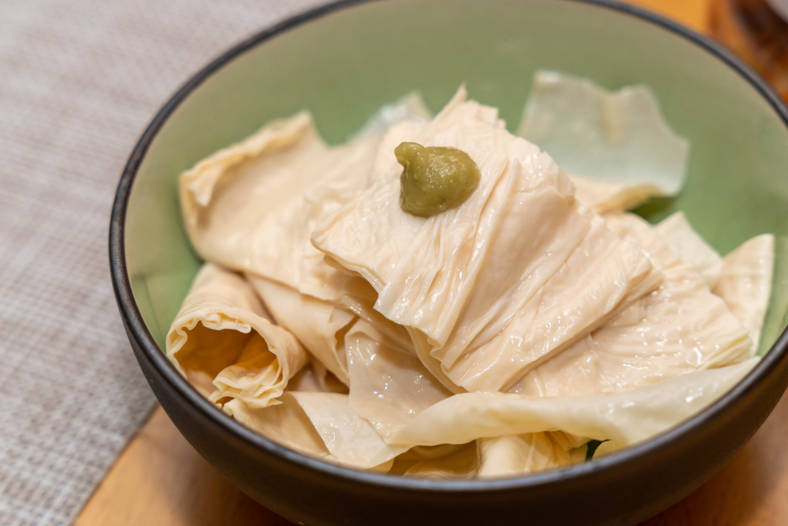 Phyllo pastry sheets piled in a green bowl with a small dollop of green sauce on top.