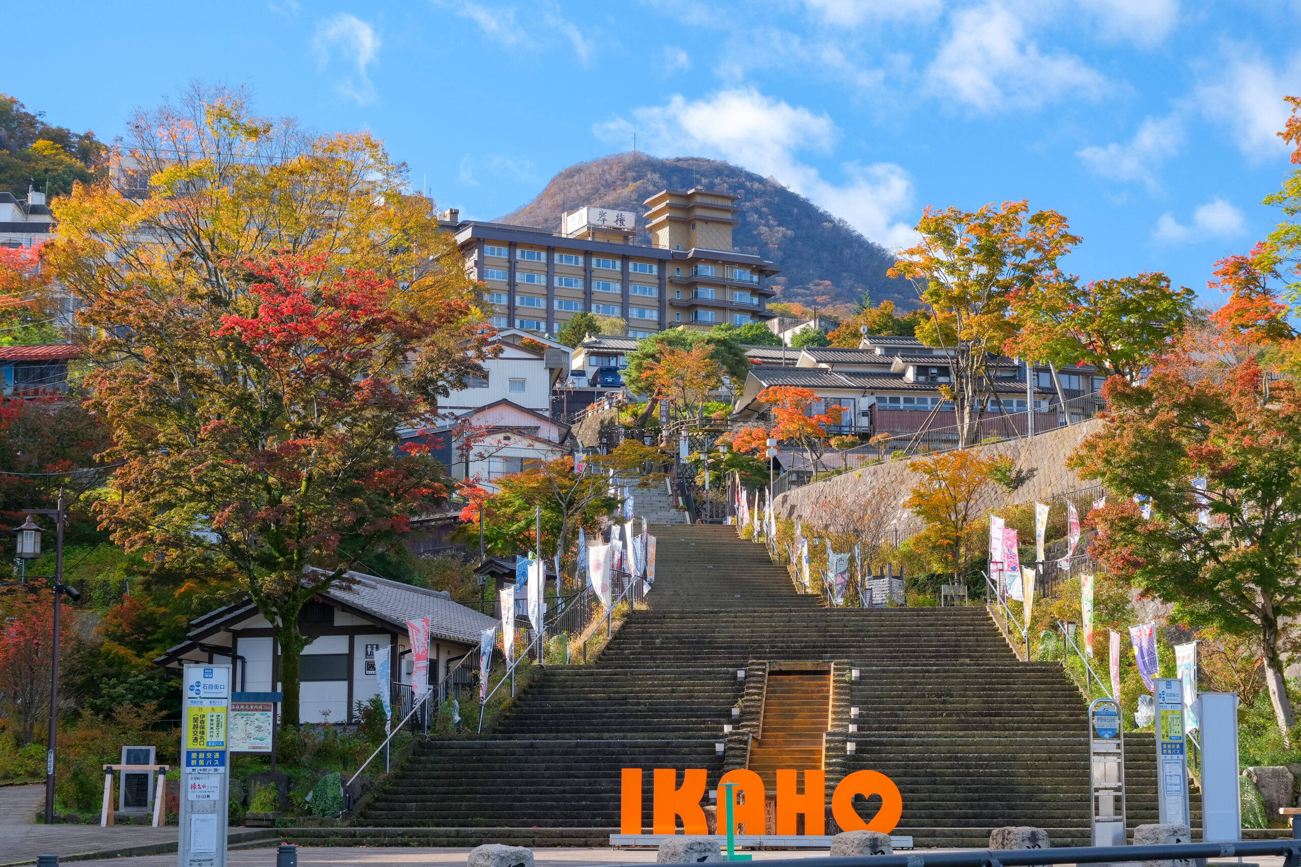 Staircase through a fall-colored avenue toward a cluster of buildings, with orange 'I ♥ KUHO' letters at the base.