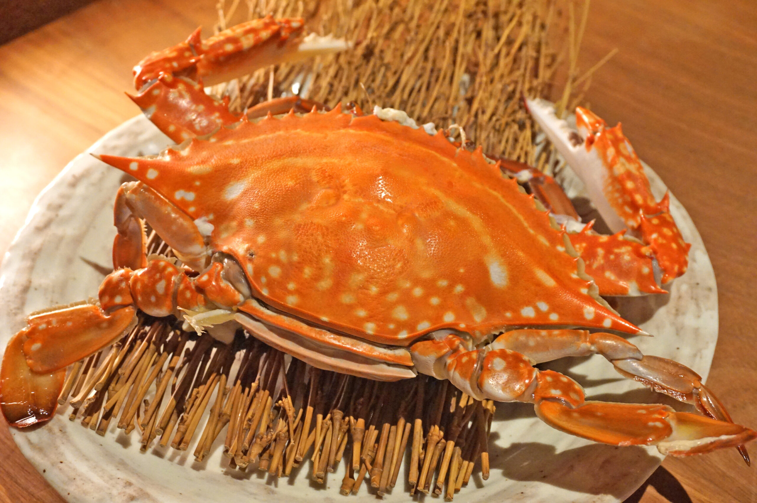 Cooked bright orange crab on a white plate with bamboo skewers underneath.