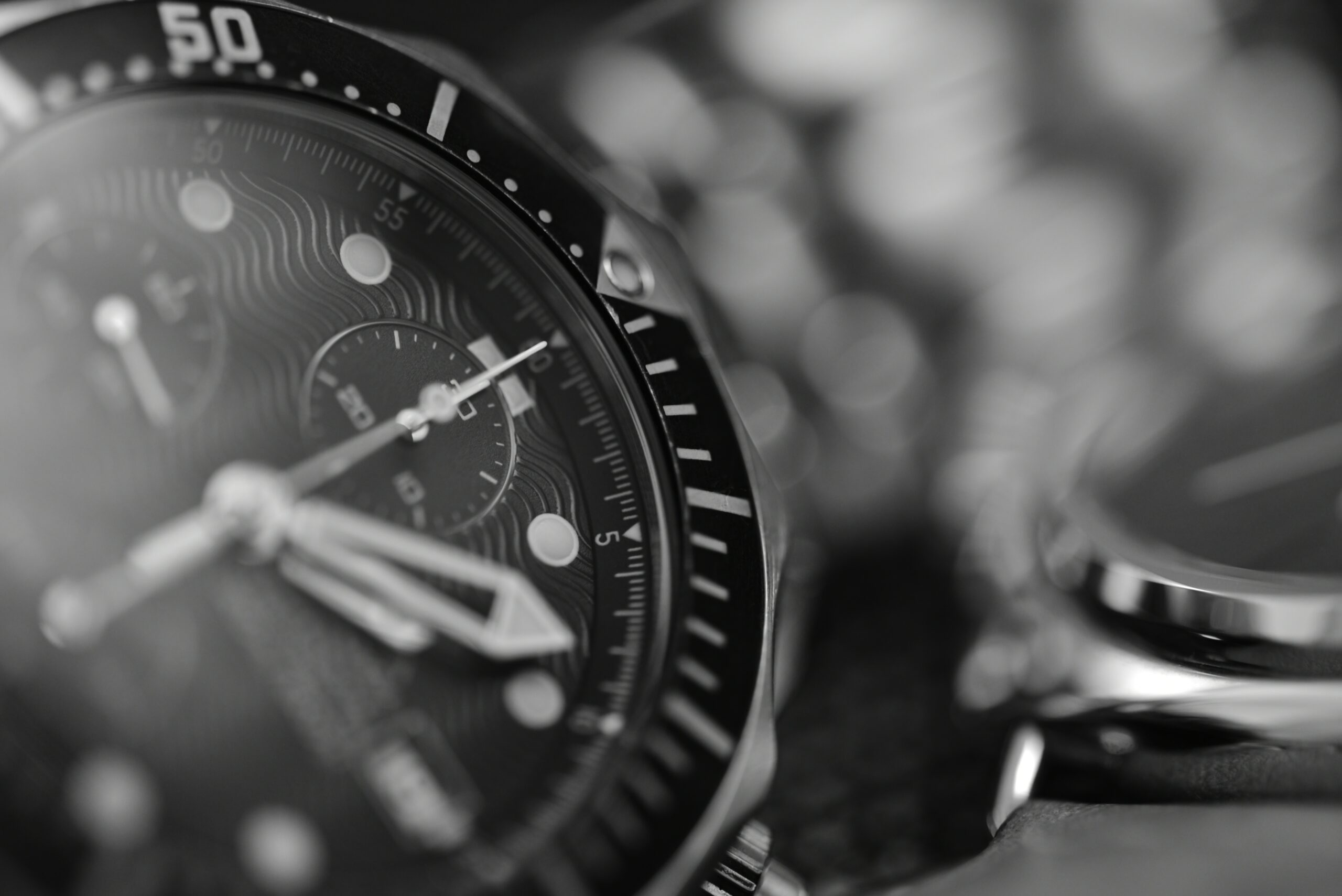 Close-up of a black wristwatch dial and rotating bezel, showing gears and markers in grayscale.