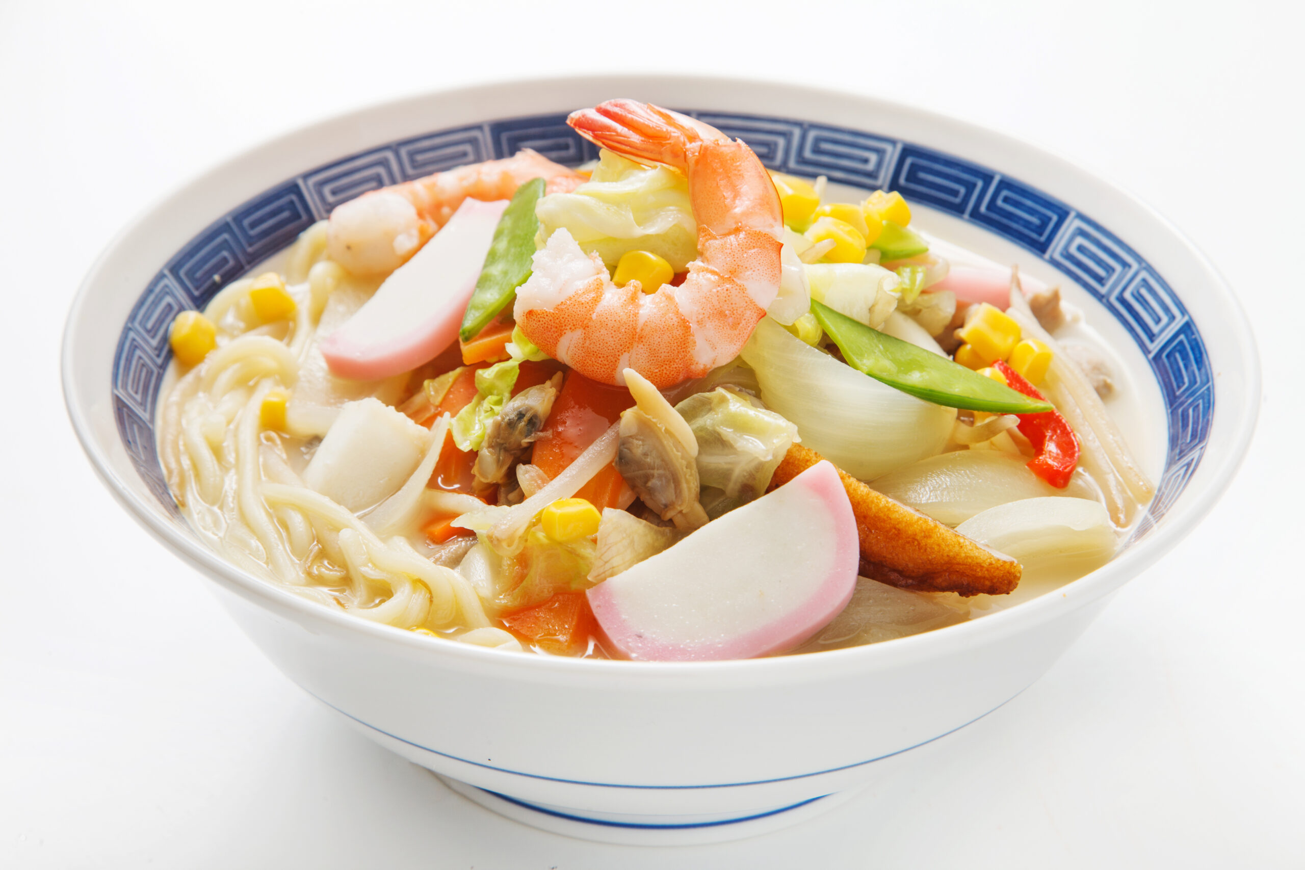 Bowl of ramen with shrimp, corn, crab sticks, and vegetables in a blue patterned bowl.
