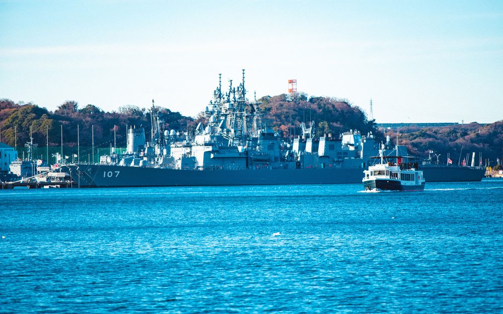 YOKOSUKA軍港めぐりの遊覧船と、横須賀港に停泊する海上自衛隊の護衛艦